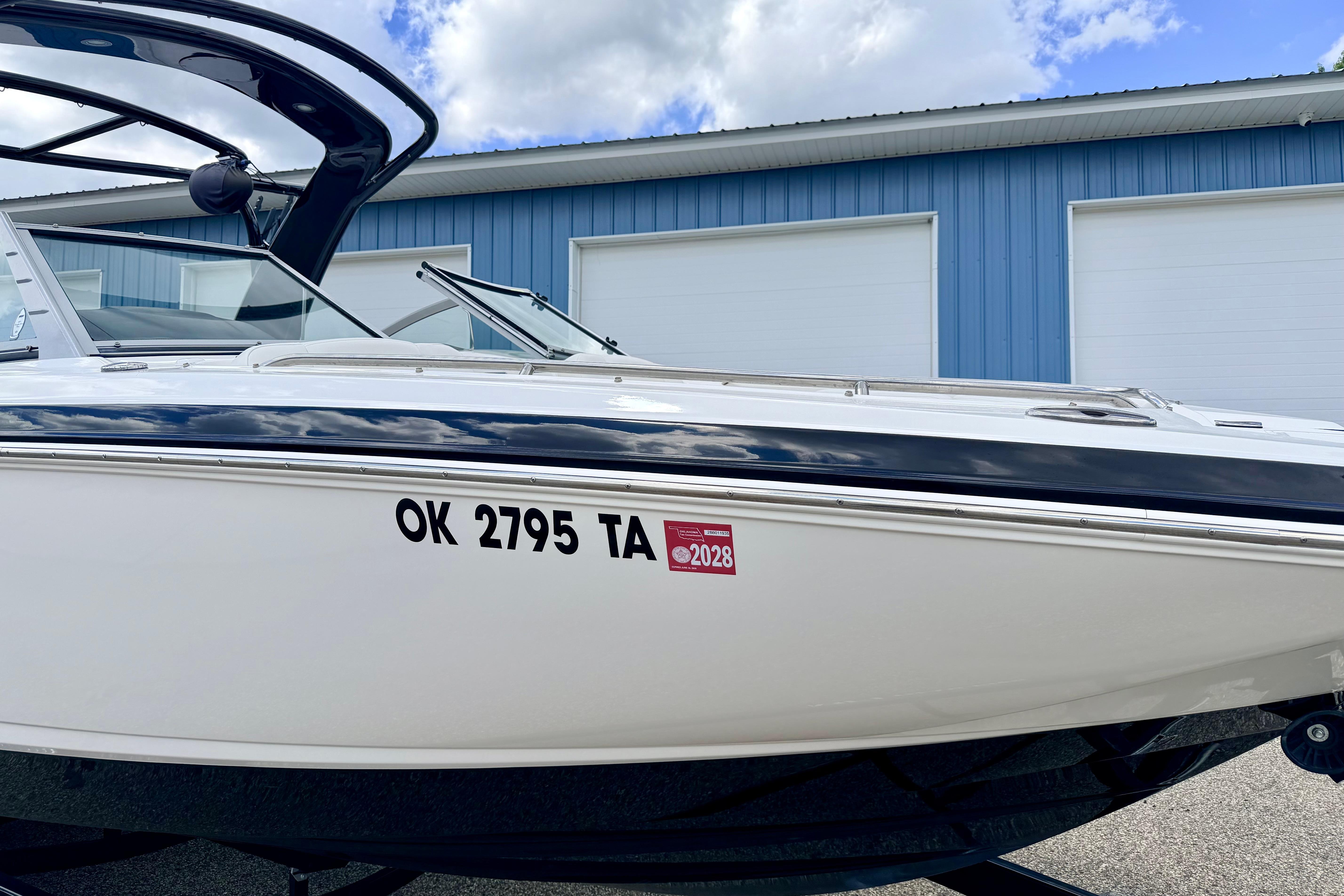 2015 Chaparral Sunesta 264 boat with registration number, parked near blue building.