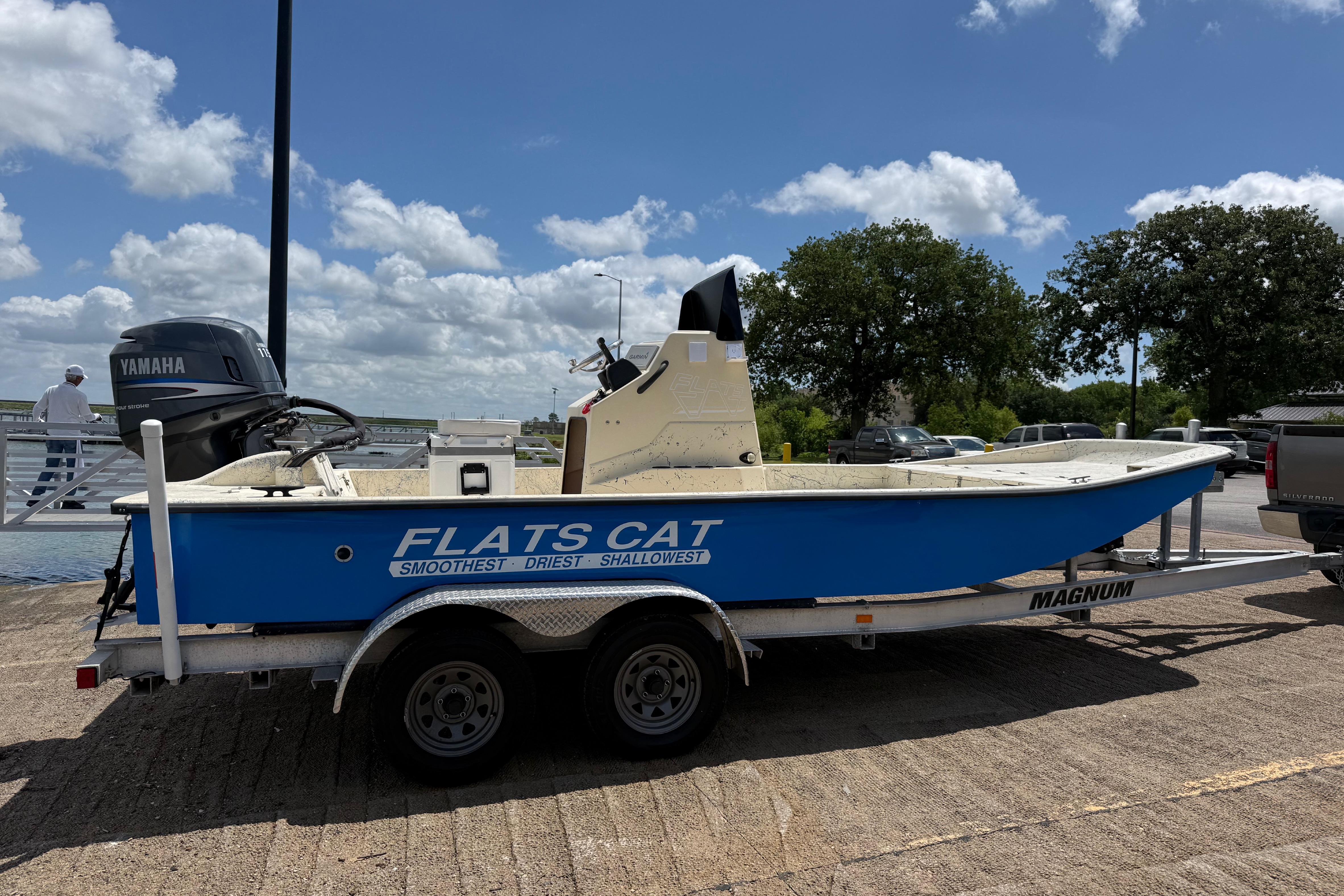 2007 Flats Cat 19 boat on trailer, featuring Yamaha engine, parked near water under blue sky.
