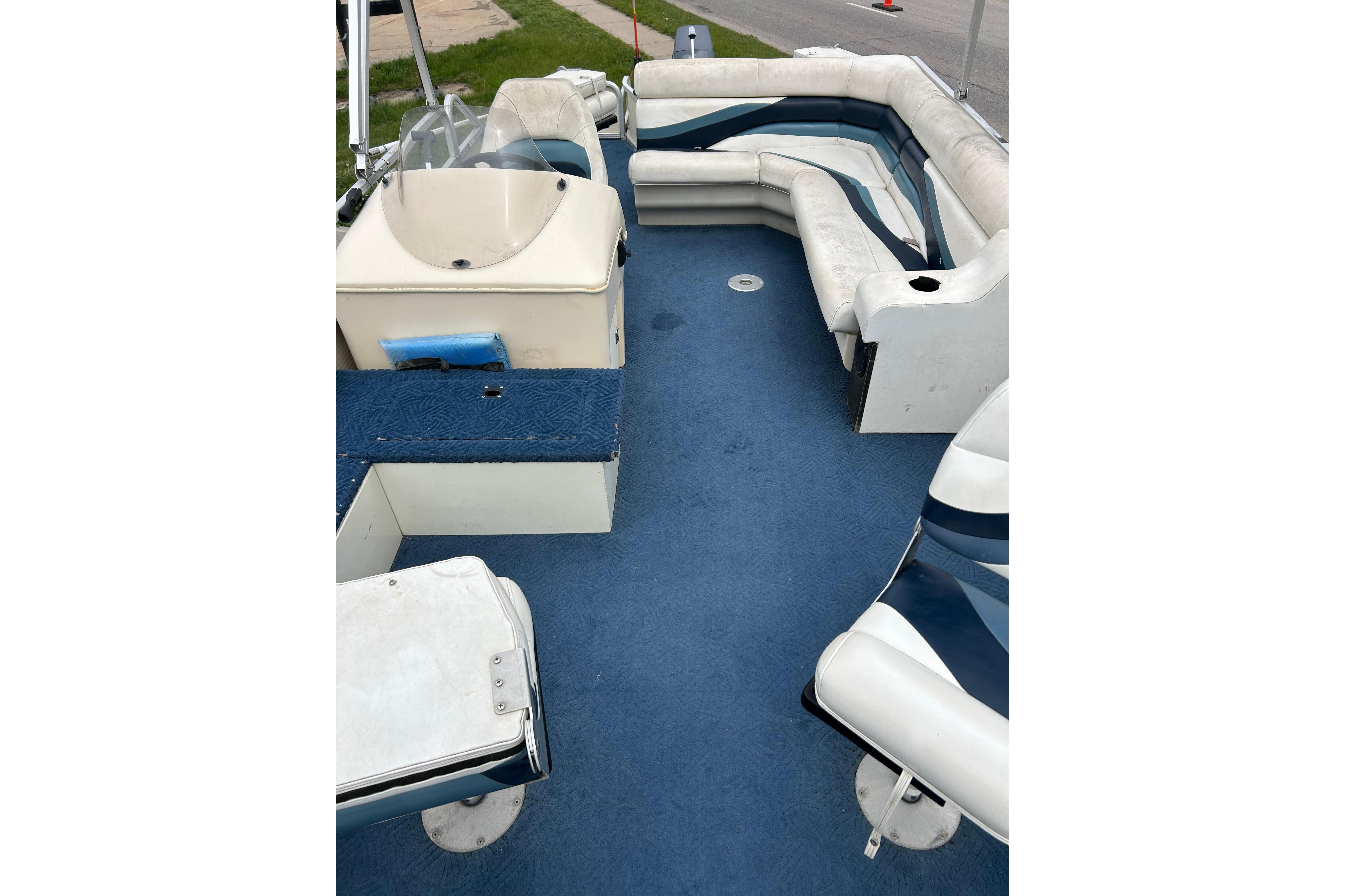 Interior of 2002 Lowe Trinidad 200 boat with blue carpet and white seating.