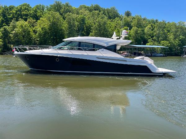 2019 Tiara Yachts C53 cruising on a lake with lush green trees in the background.