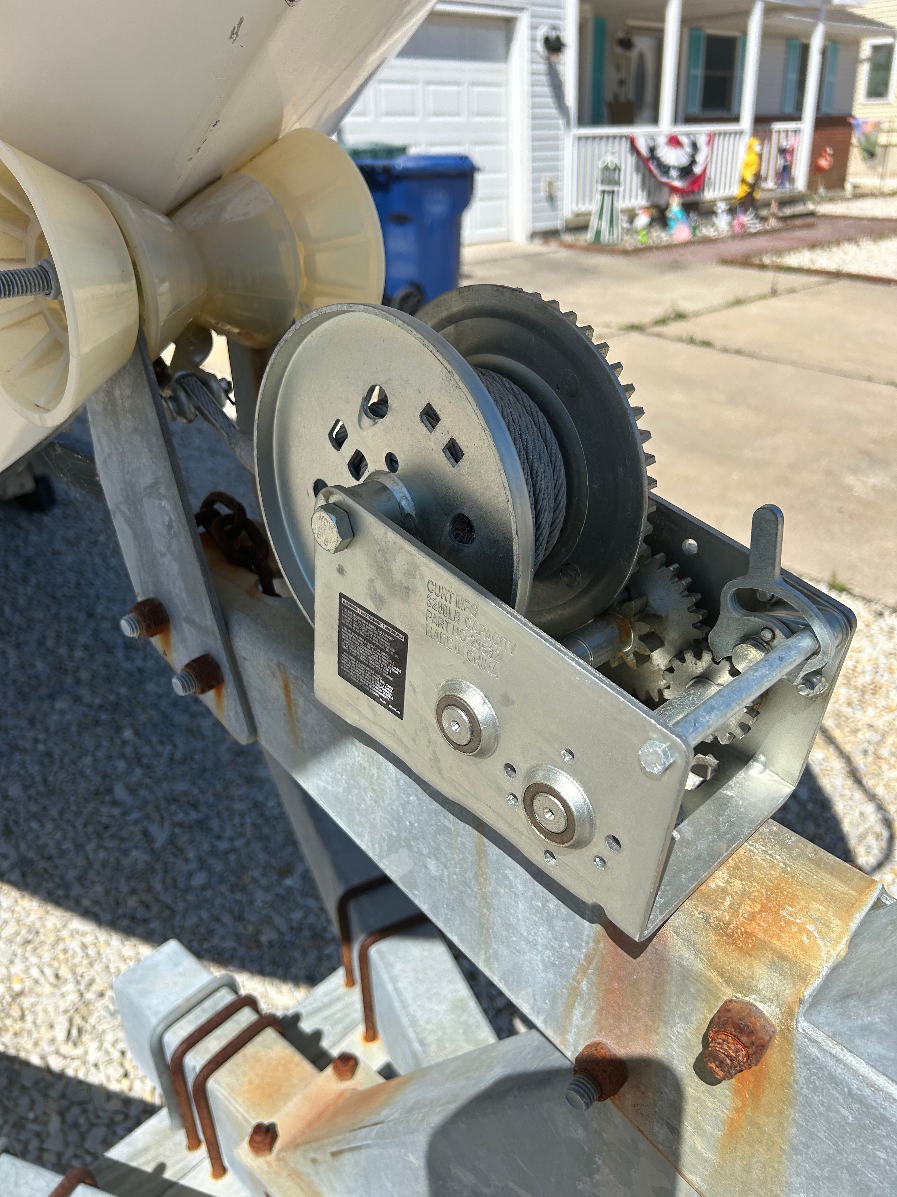 Close-up of a winch on a boat trailer, surrounded by a residential area.