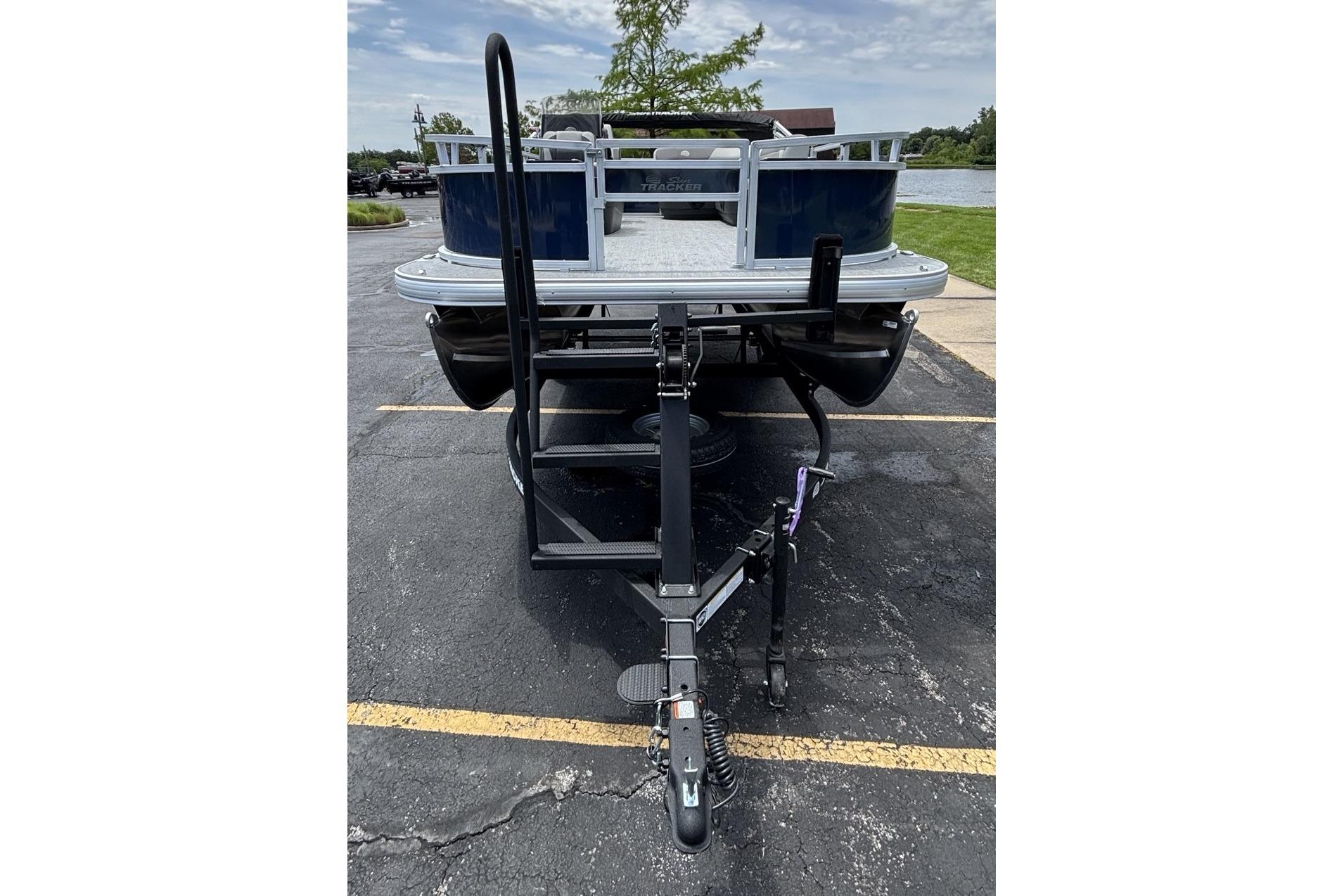 2026 Sun Tracker Bass Buggy 16 XL Select pontoon boat on trailer in parking lot.