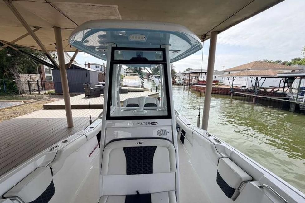 2024 Tidewater 232 LXF boat docked, showcasing sleek interior and waterfront setting.