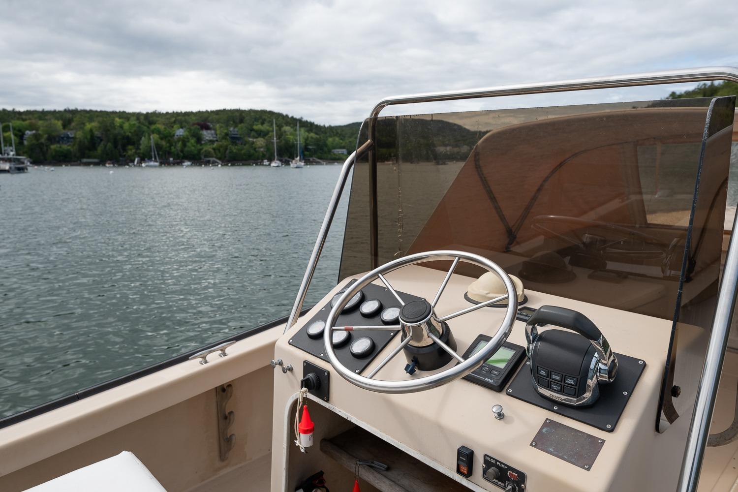 1989 Ellis 24 Open boat dashboard with steering wheel, controls, and scenic lake view.