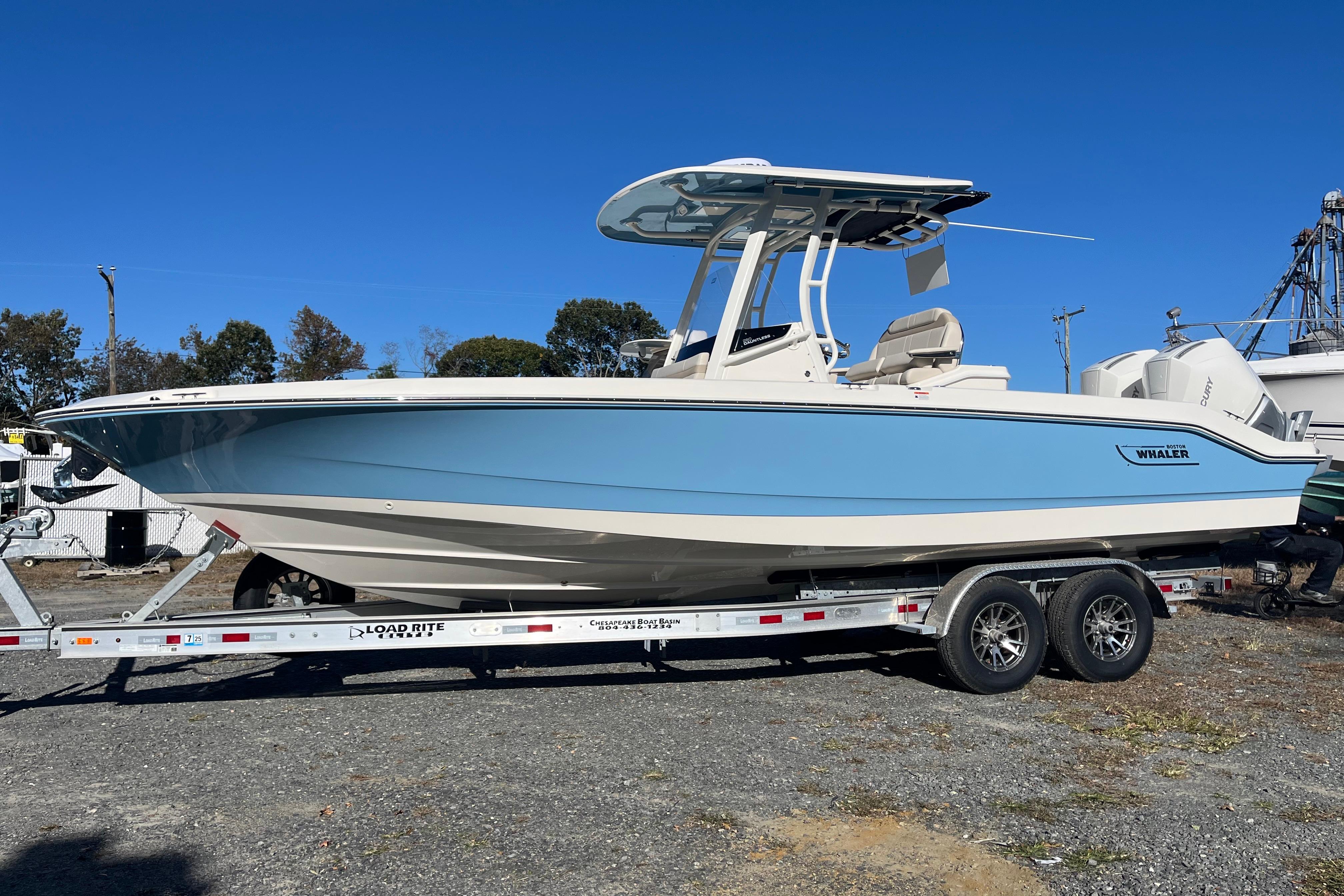 2026 Boston Whaler 280 Dauntless boat on trailer, light blue hull, clear sky background.