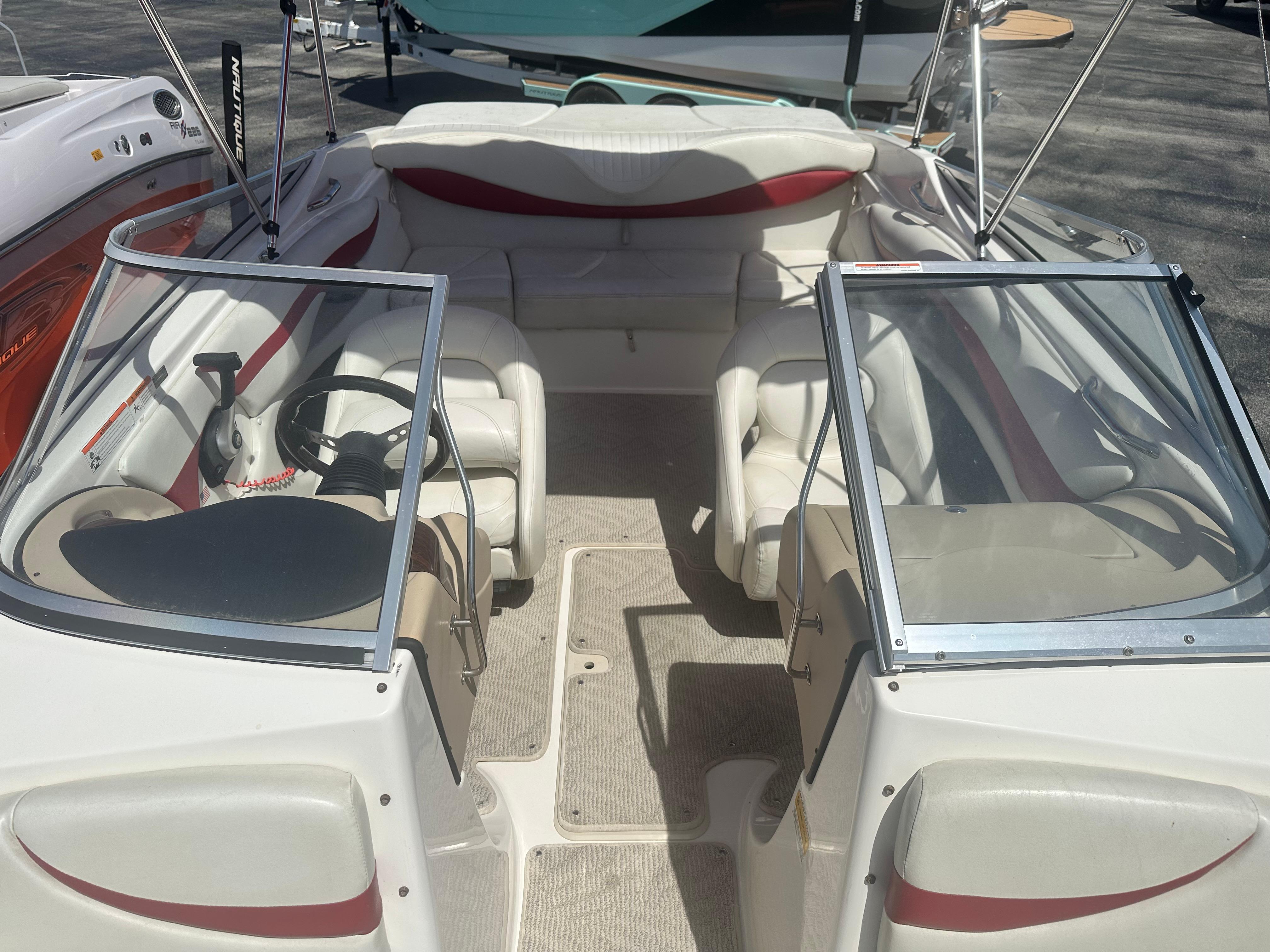 2008 Glastron 205 GX boat interior with white and red seating, steering wheel, and open windshield.