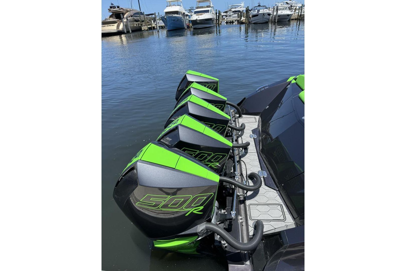 Four green and black 500R outboard motors on a 2023 Adrenaline 47 boat at a marina.