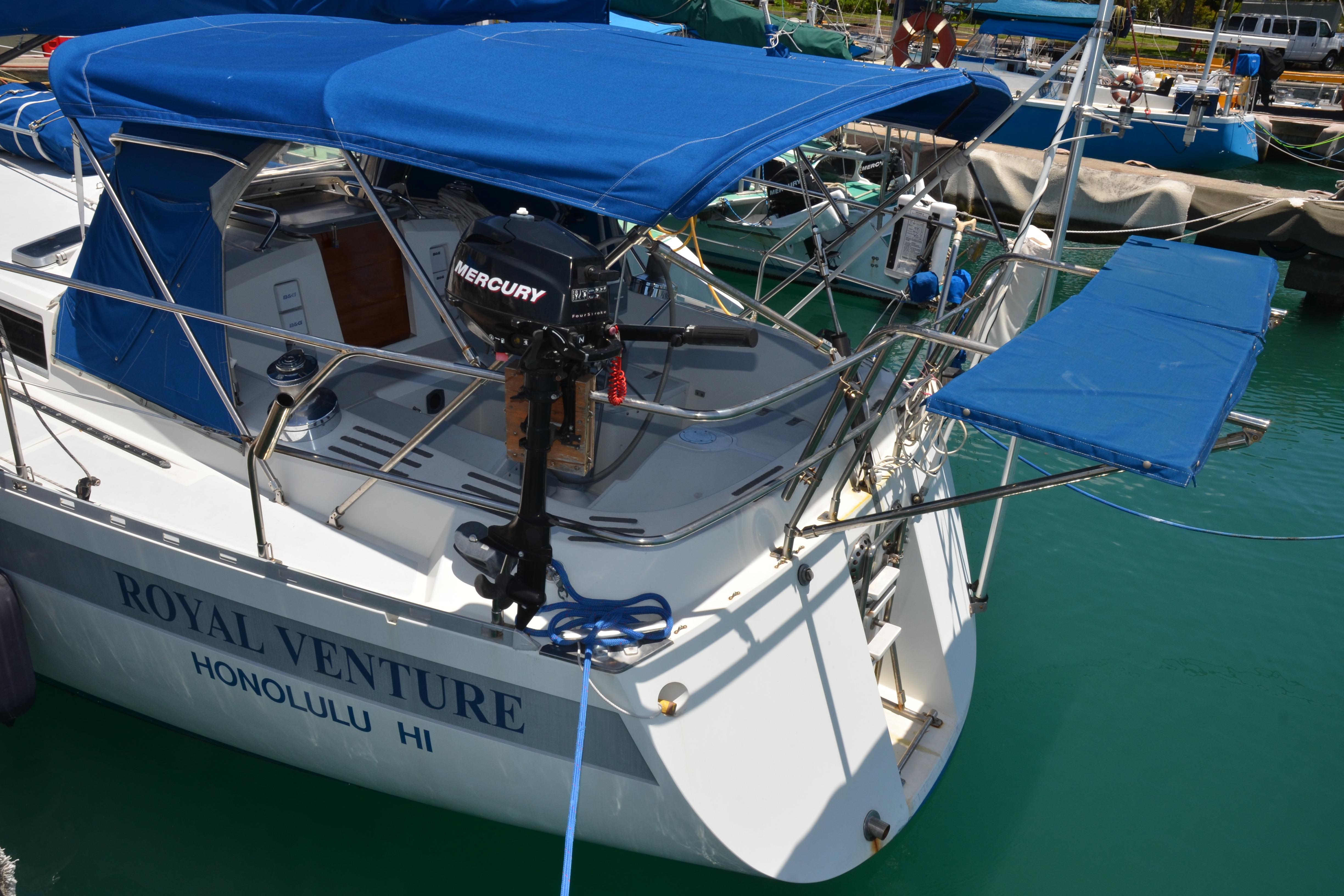 Sailboat "Royal Venture" docked in Honolulu, featuring blue canopy and Mercury motor.