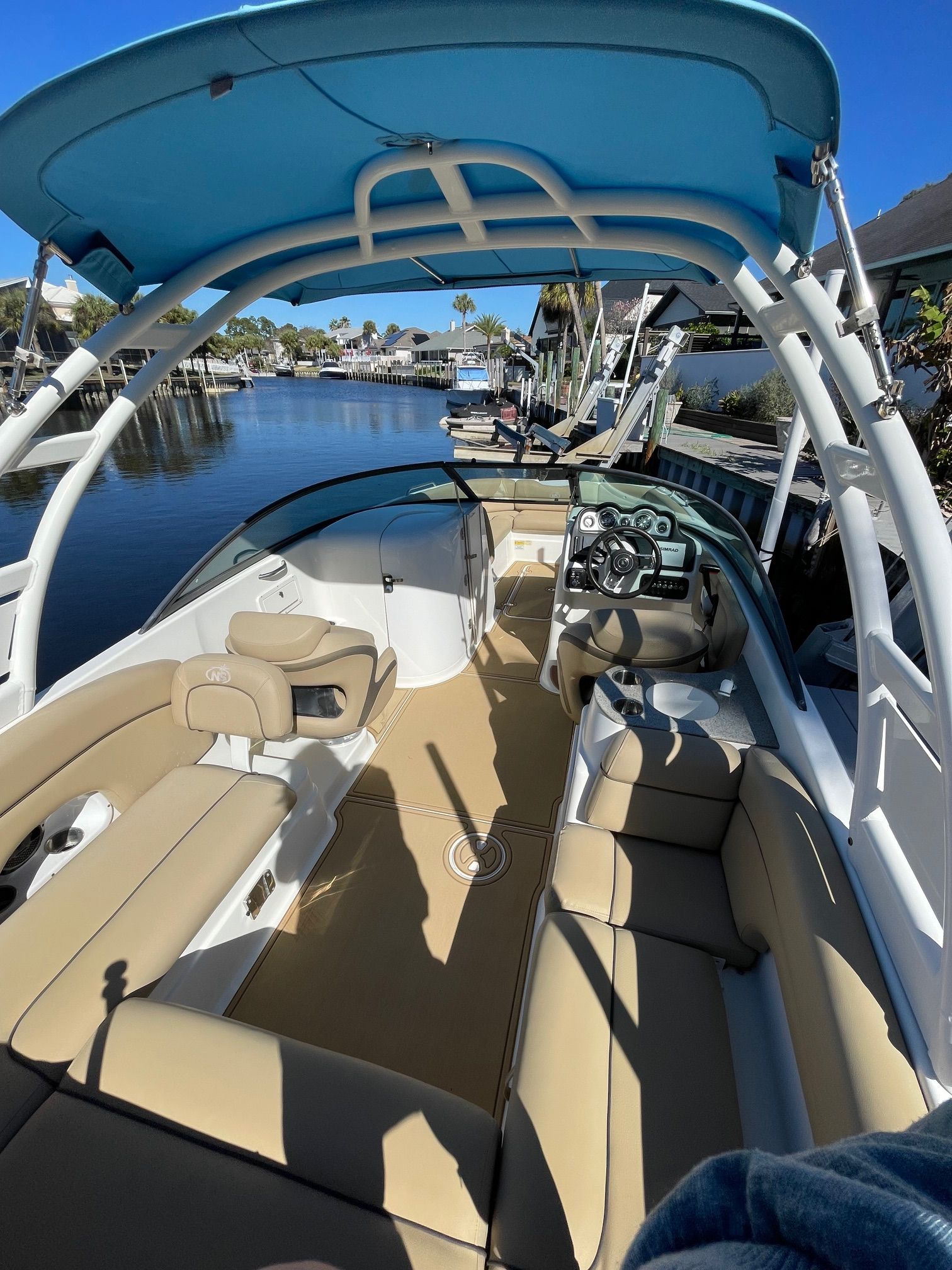 2019 NauticStar 243DC Sport Deck with blue sunshade, docked on calm water.