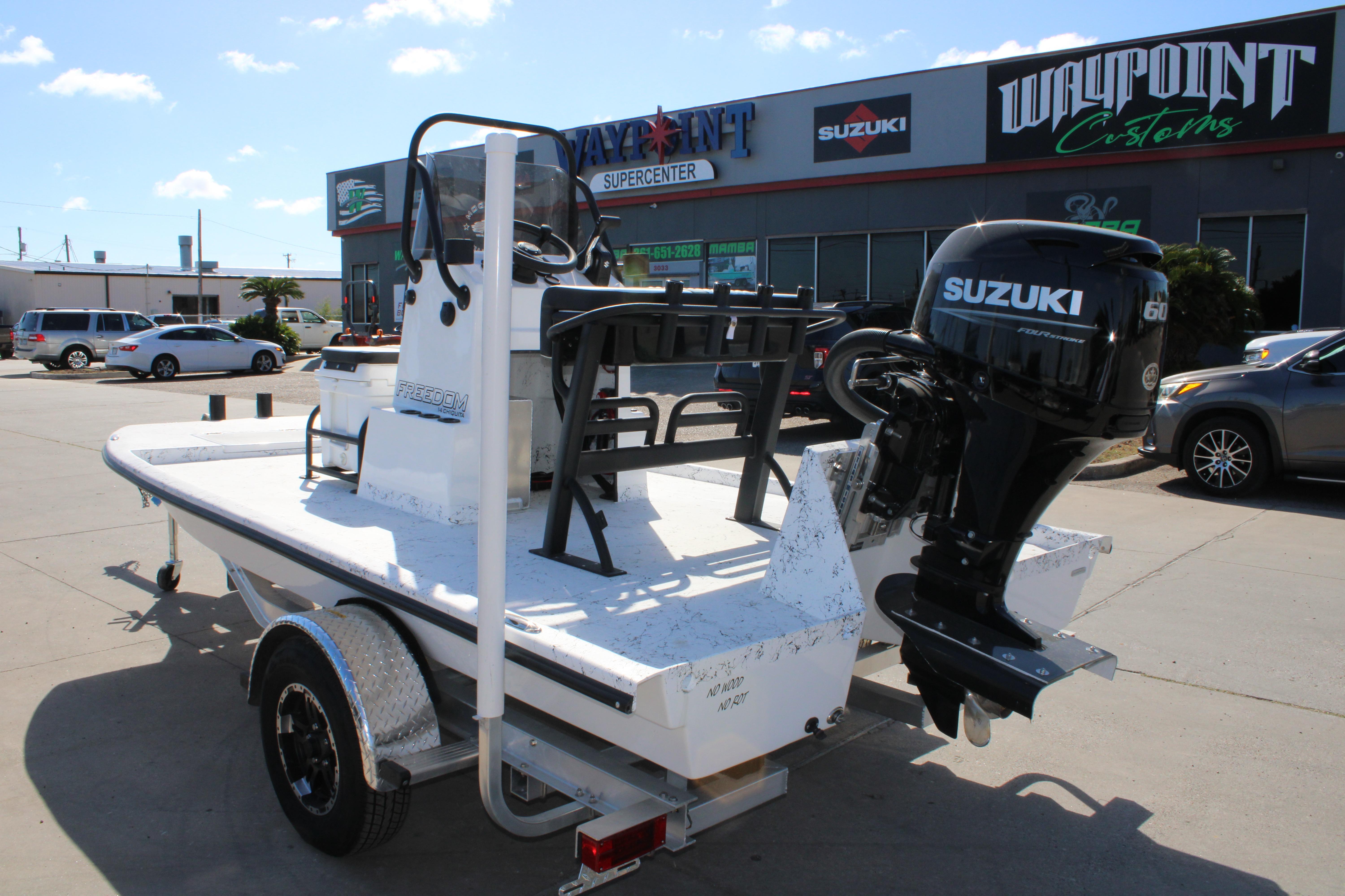 2026 Freedom Boats Chiquita with Suzuki engine on trailer at dealership.