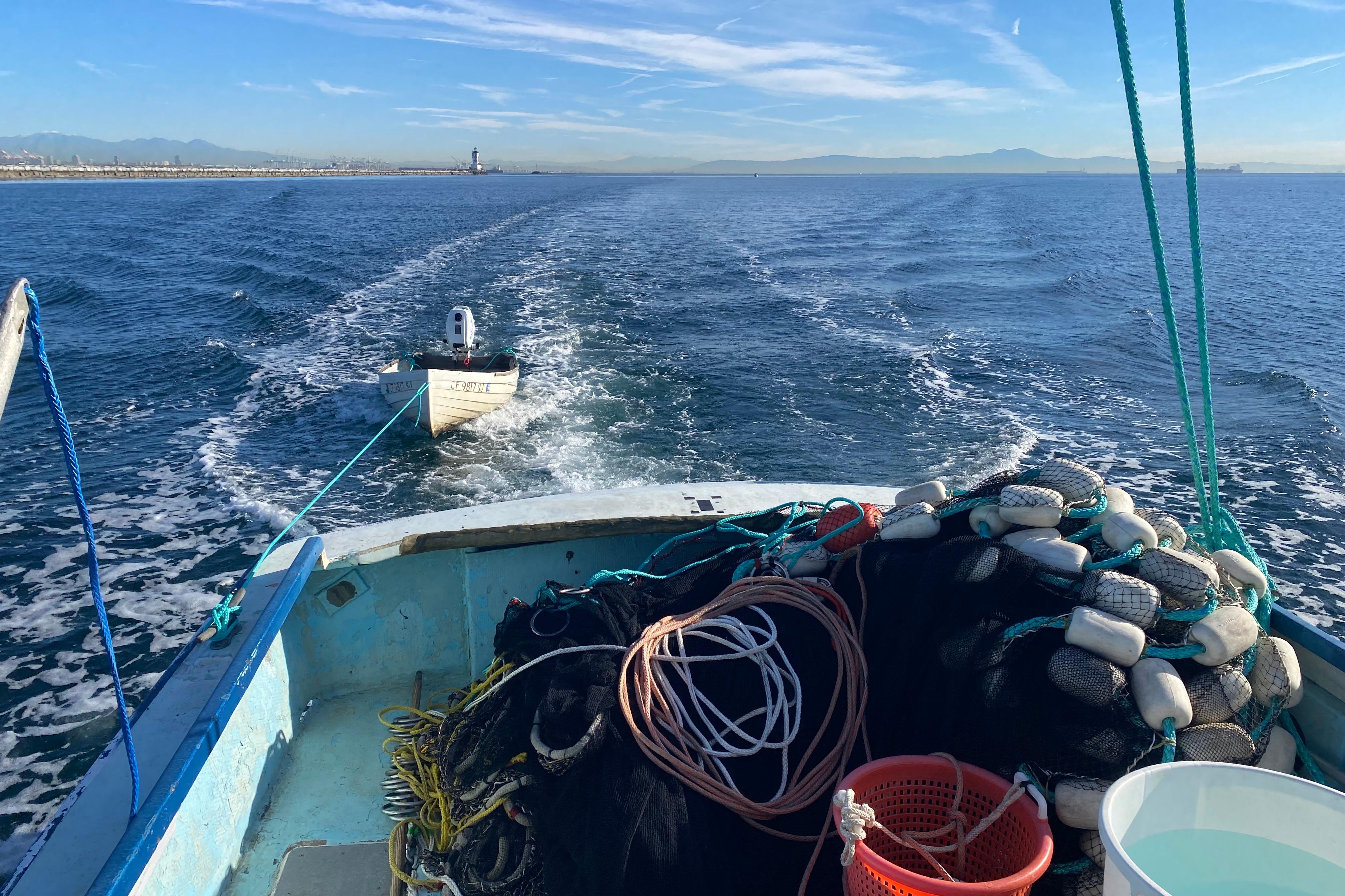 Fishing boat Roberts 30 (1977) towing a small dinghy on open water.