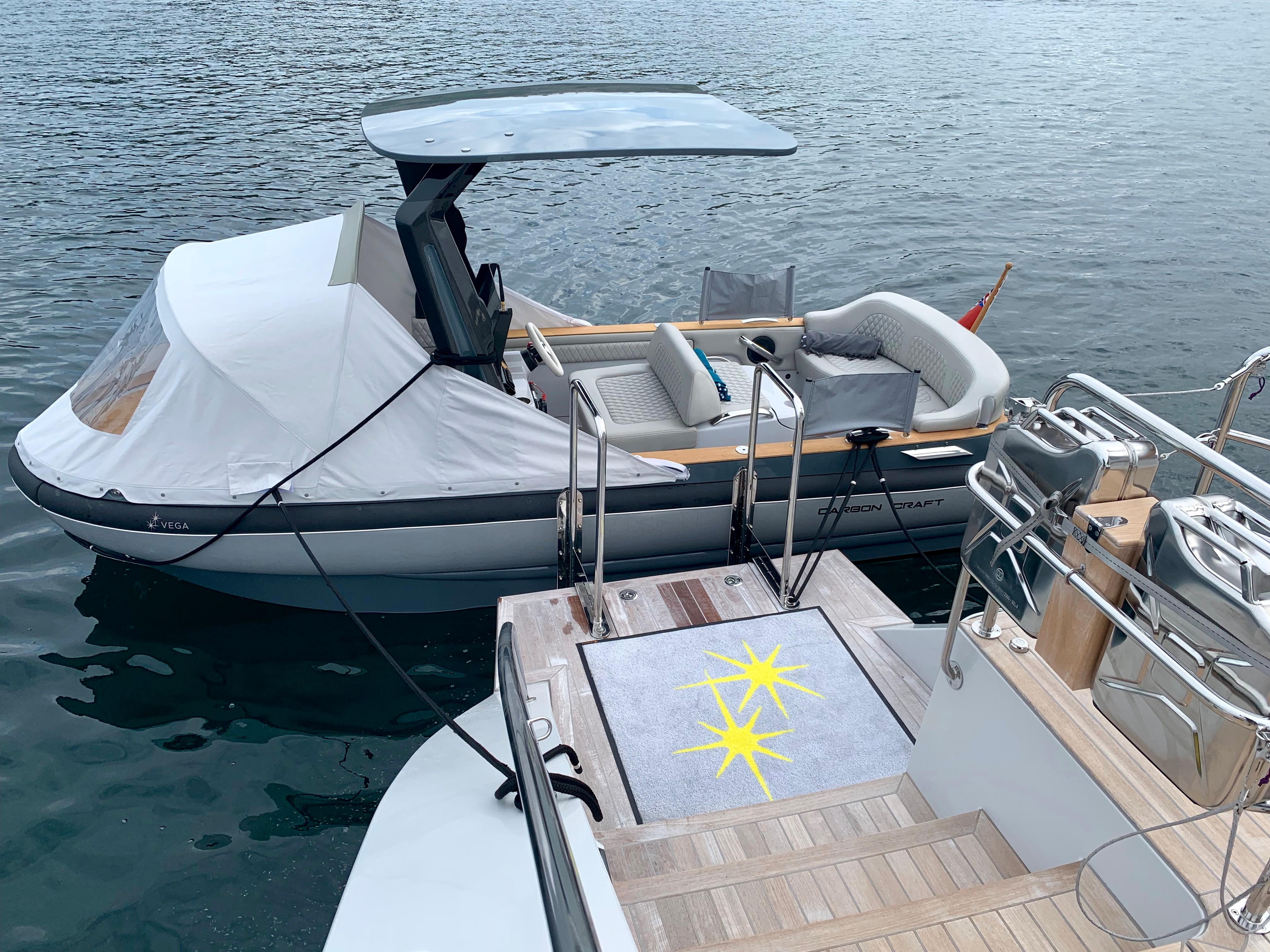 Carbon Craft CC 160 boat, 2016 model, docked beside a yacht on calm water.