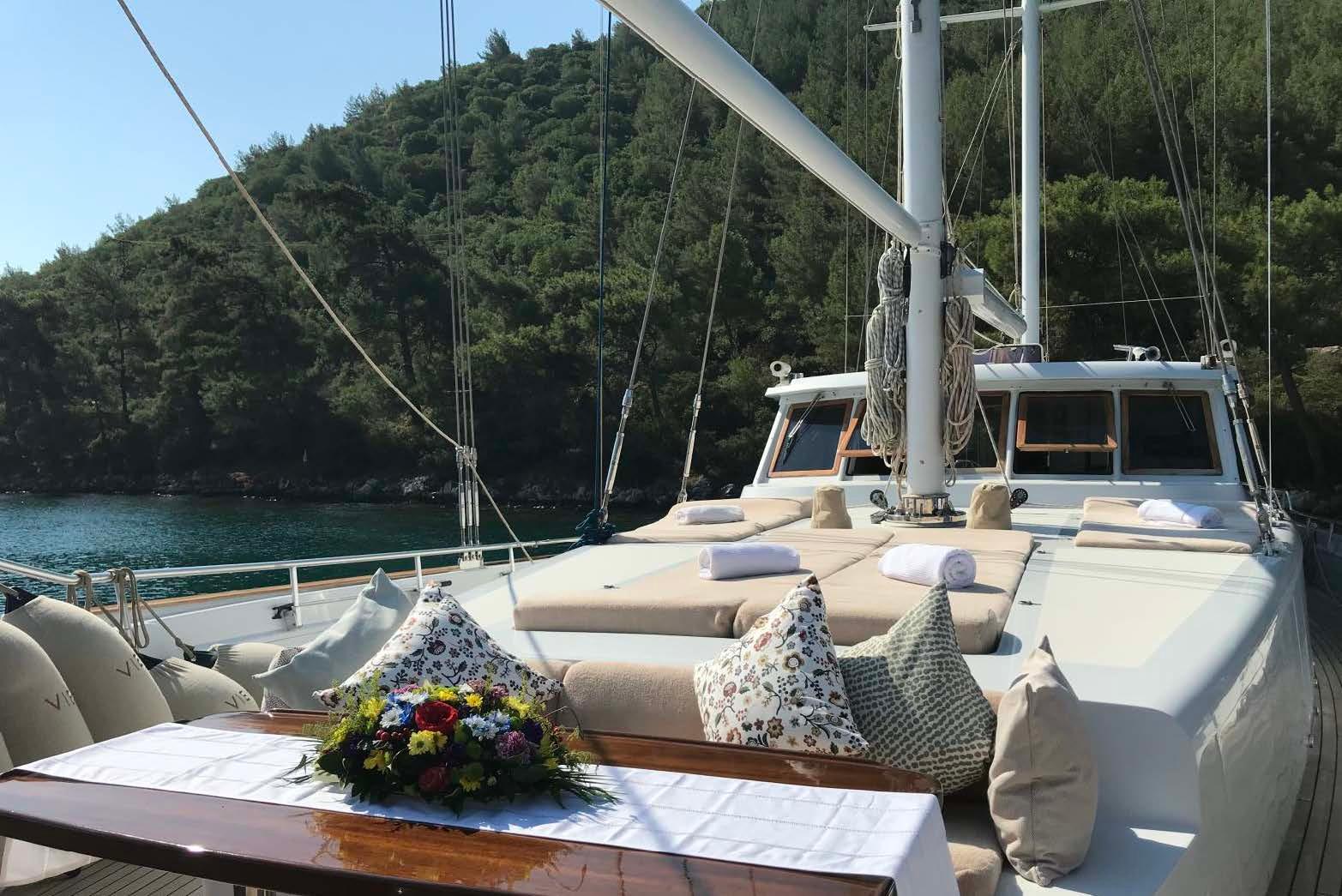 Luxurious 2006 Custom Motorsailer with deck seating, cushions, and scenic forest backdrop.