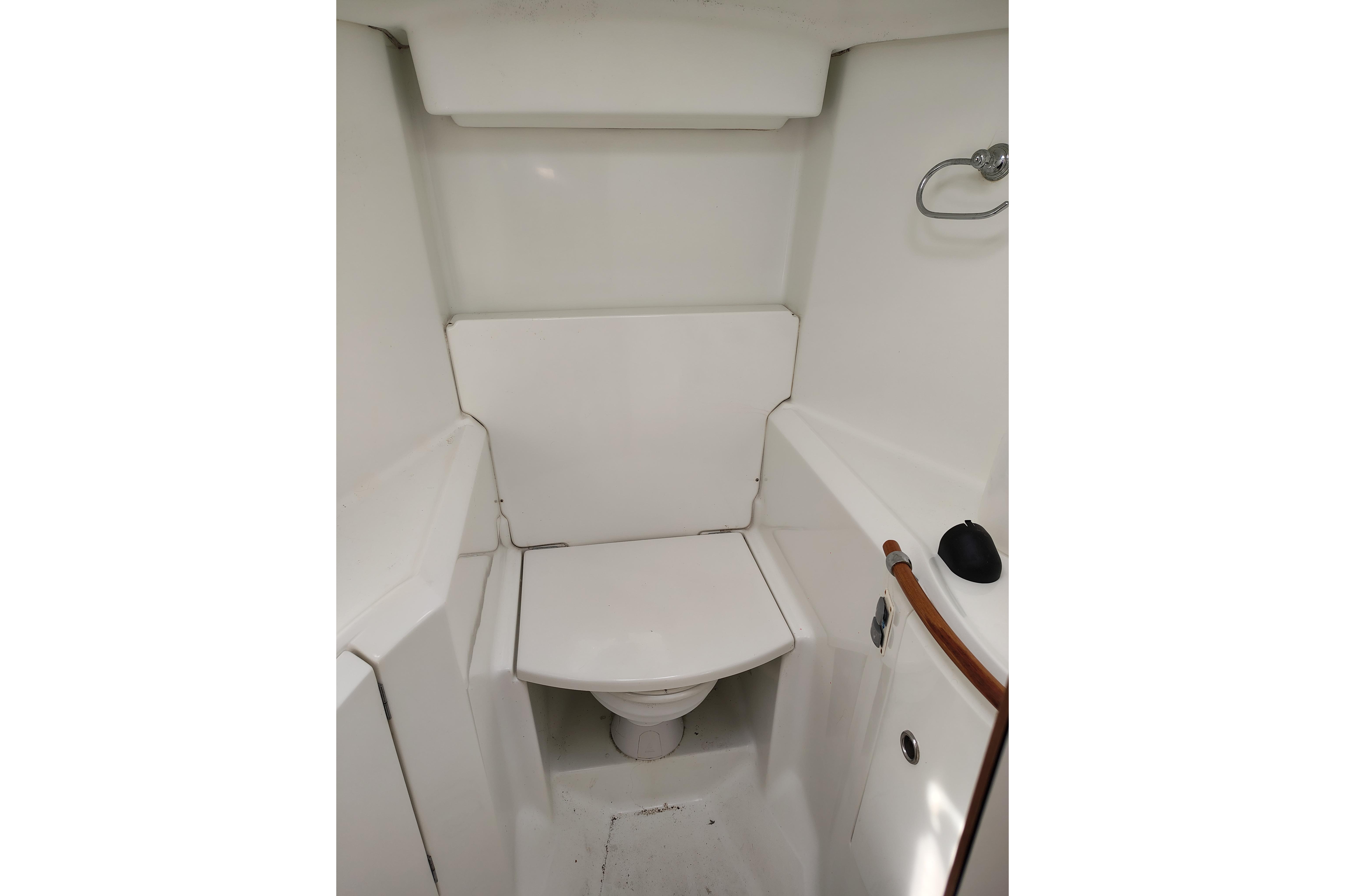 Compact bathroom in 2001 Beneteau Oceanis 411 sailboat, featuring a white marine toilet.
