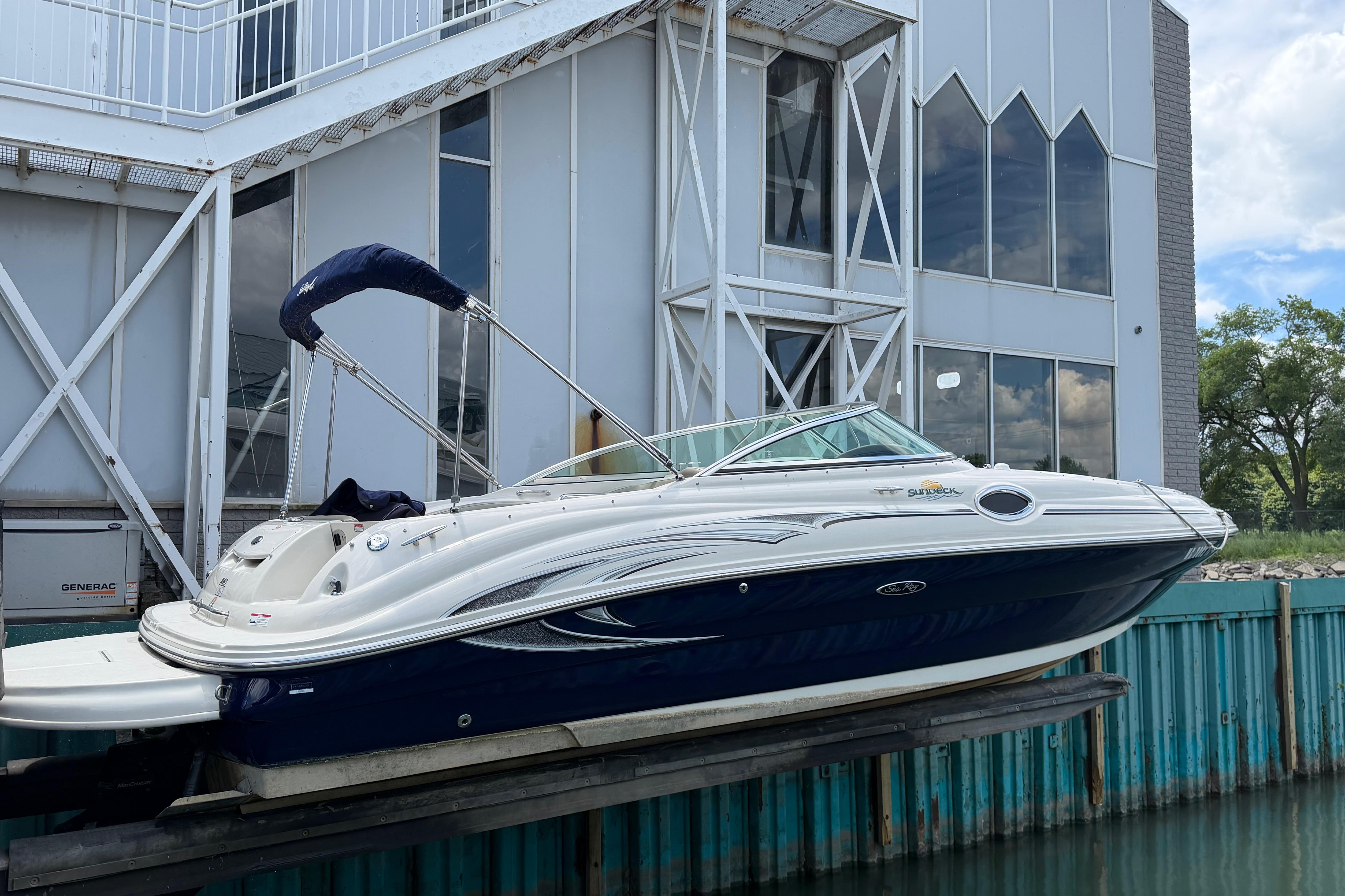 2004 Sea Ray 240 Sundeck boat docked near modern building.