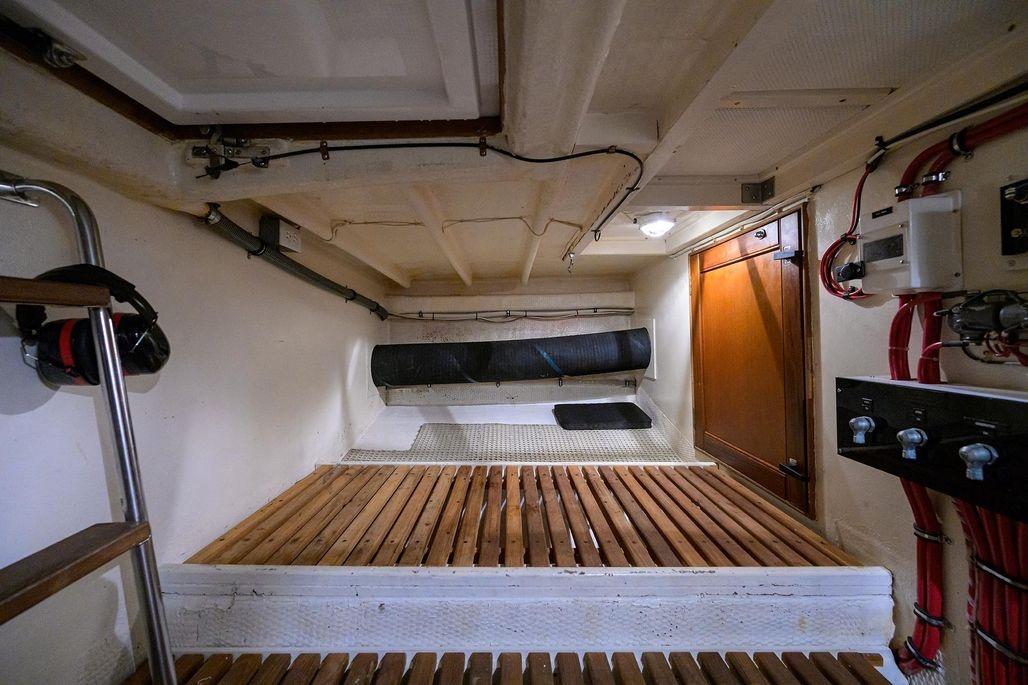 Engine room of 1999 Grand Banks 42 Europa yacht, featuring wooden flooring and control panels.