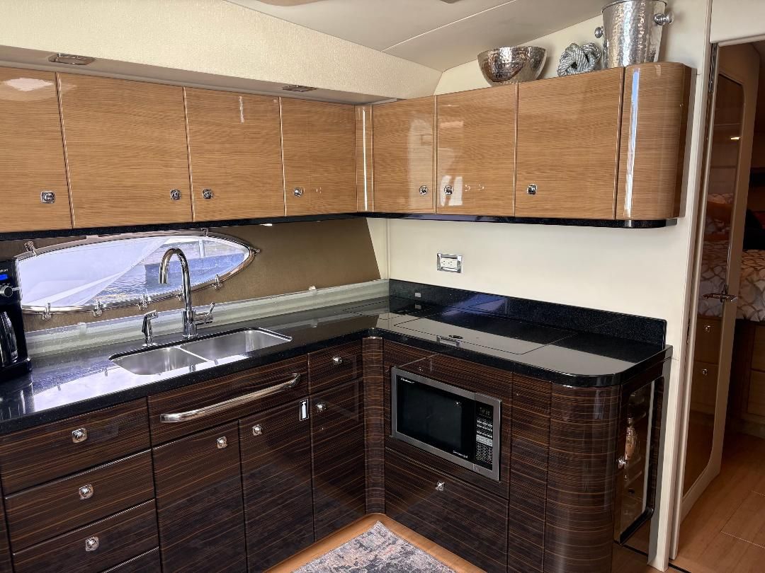 Interior of a 2011 Formula 45 with sleek kitchen, wooden cabinets, sink, and microwave.