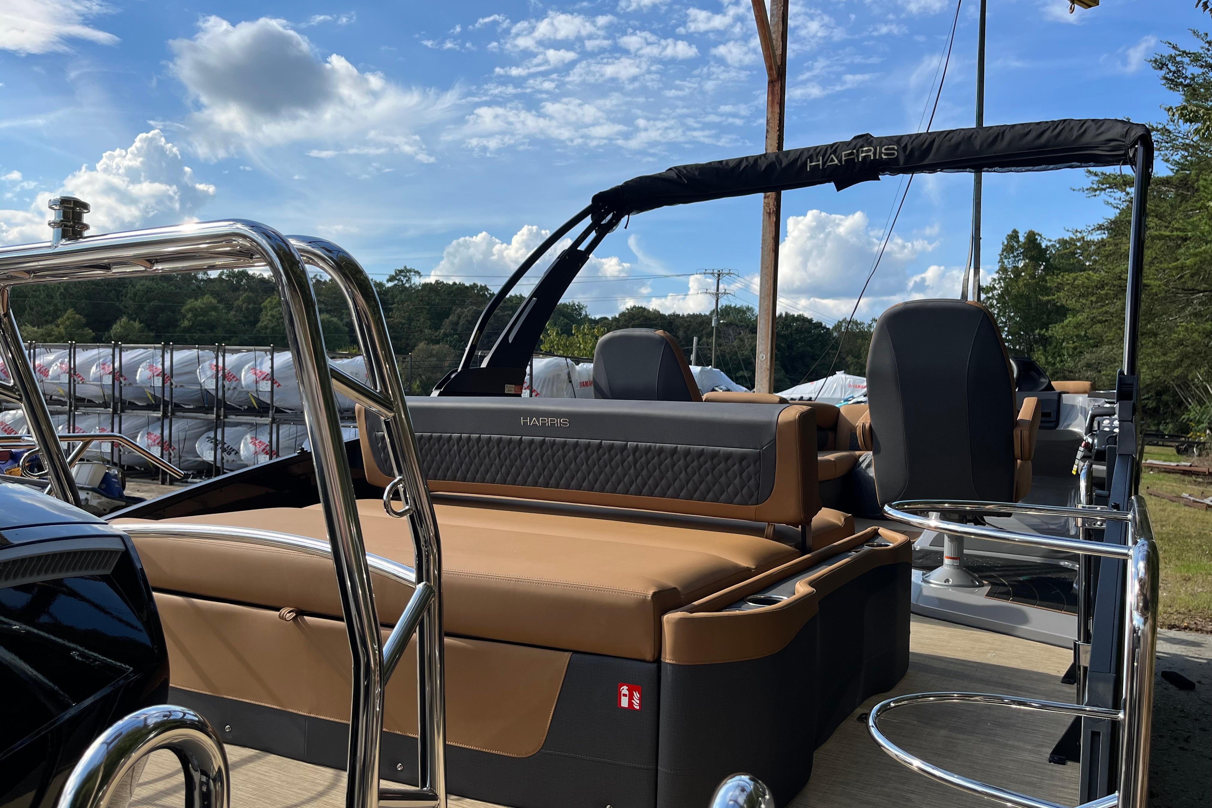 2025 Harris Sunliner 250 pontoon boat with tan seating and sleek design under a blue sky.