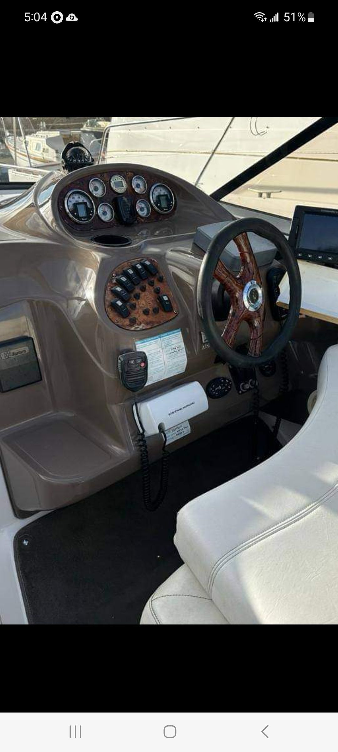 Helm of a 2004 Regal Commodore 2465 boat with wooden steering wheel.