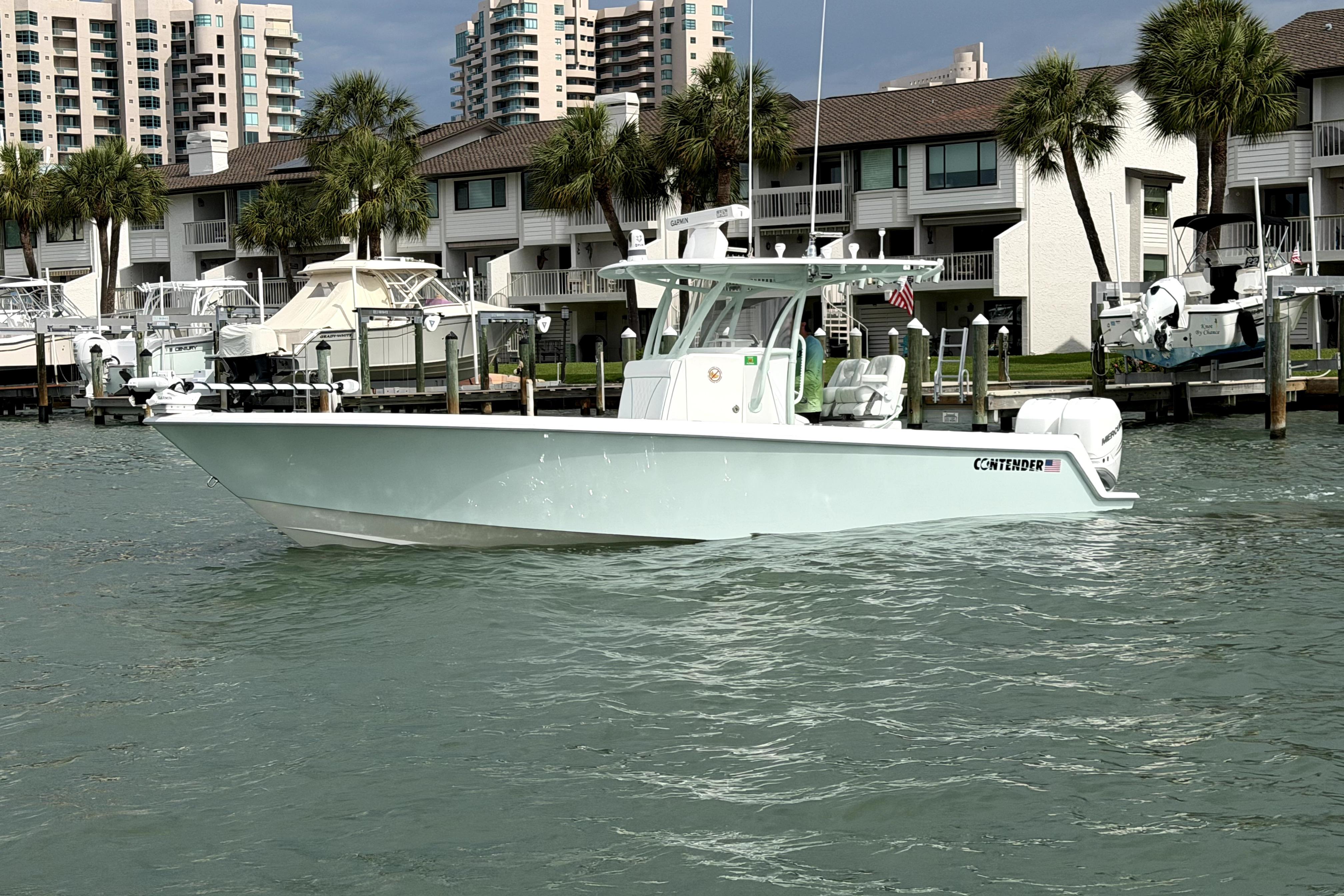 2019 Contender 30 ST boat docked near waterfront homes with palm trees.