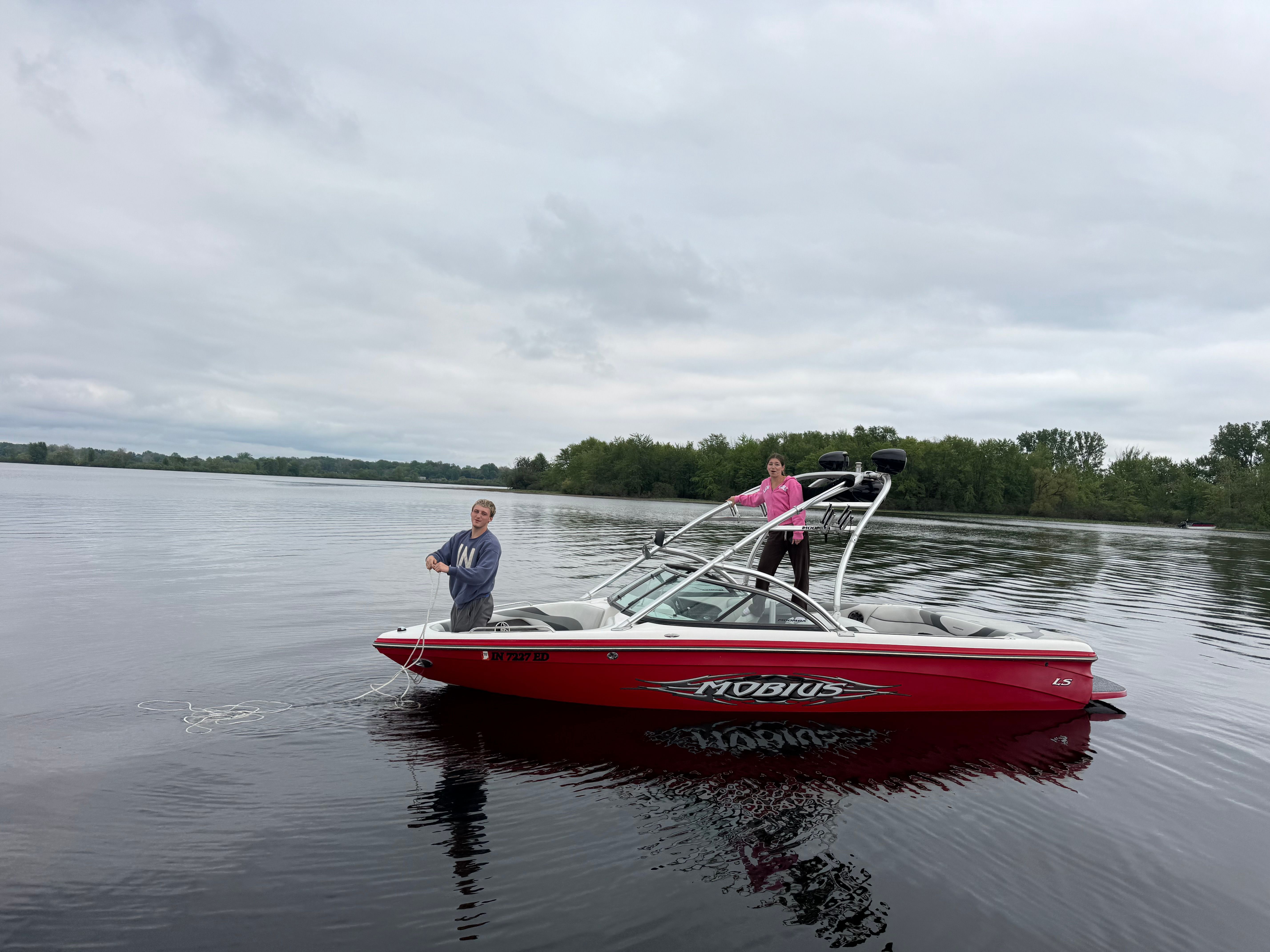 2008 Moomba Mobius LS boat on calm lake with two people.