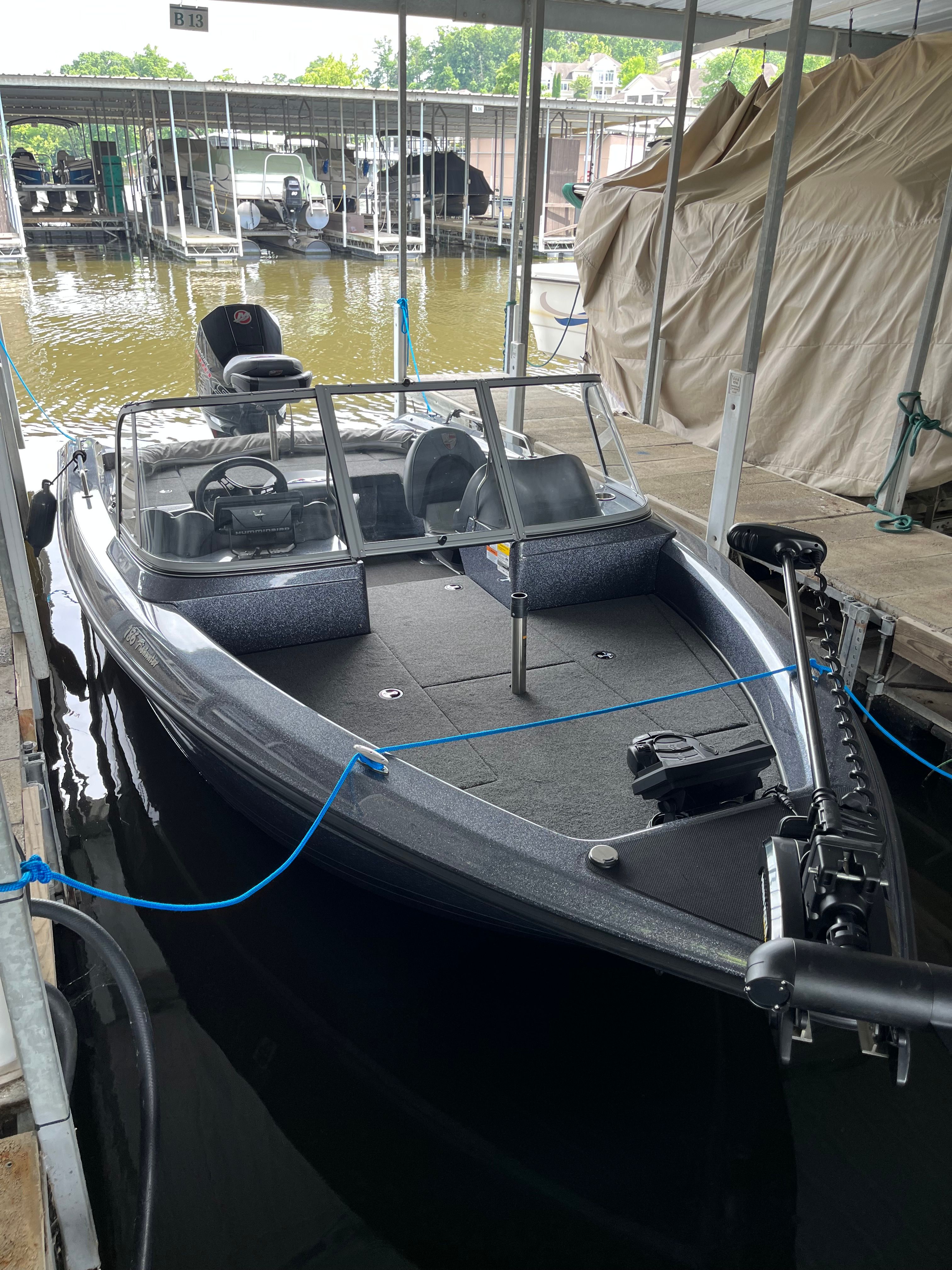 A 2023 Triton 186 Fishunter docked. It features a gray deck and windshield.