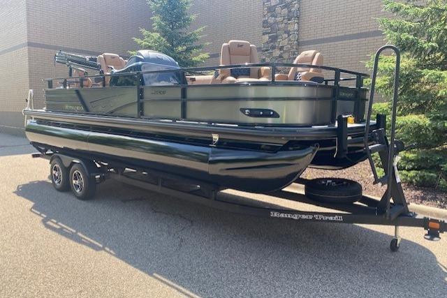 2026 Ranger 220F pontoon boat on trailer, parked outdoors near trees and building.