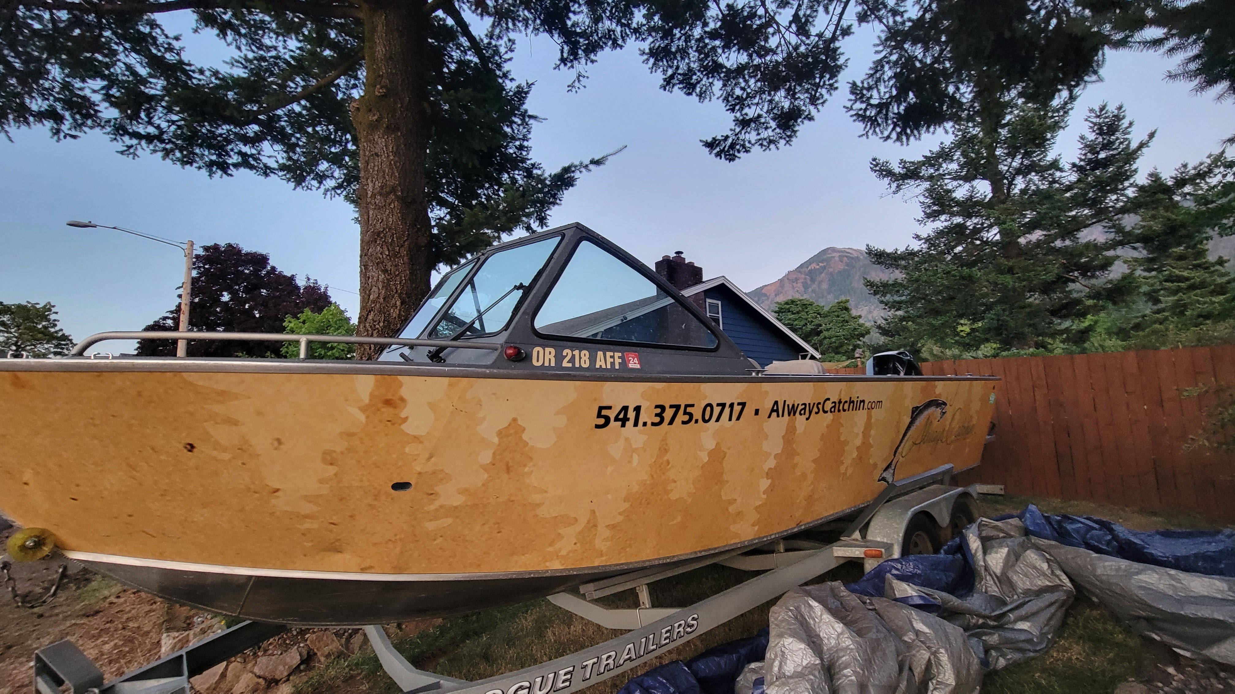 A 2015 Alumaweld Formula Vee Outboard 24 on a trailer in a wooded area.