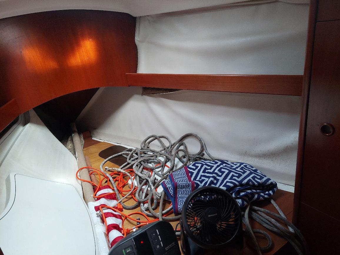 Interior of 1995 Beneteau Oceanis 351 sailboat with ropes, fan, and patterned bag.