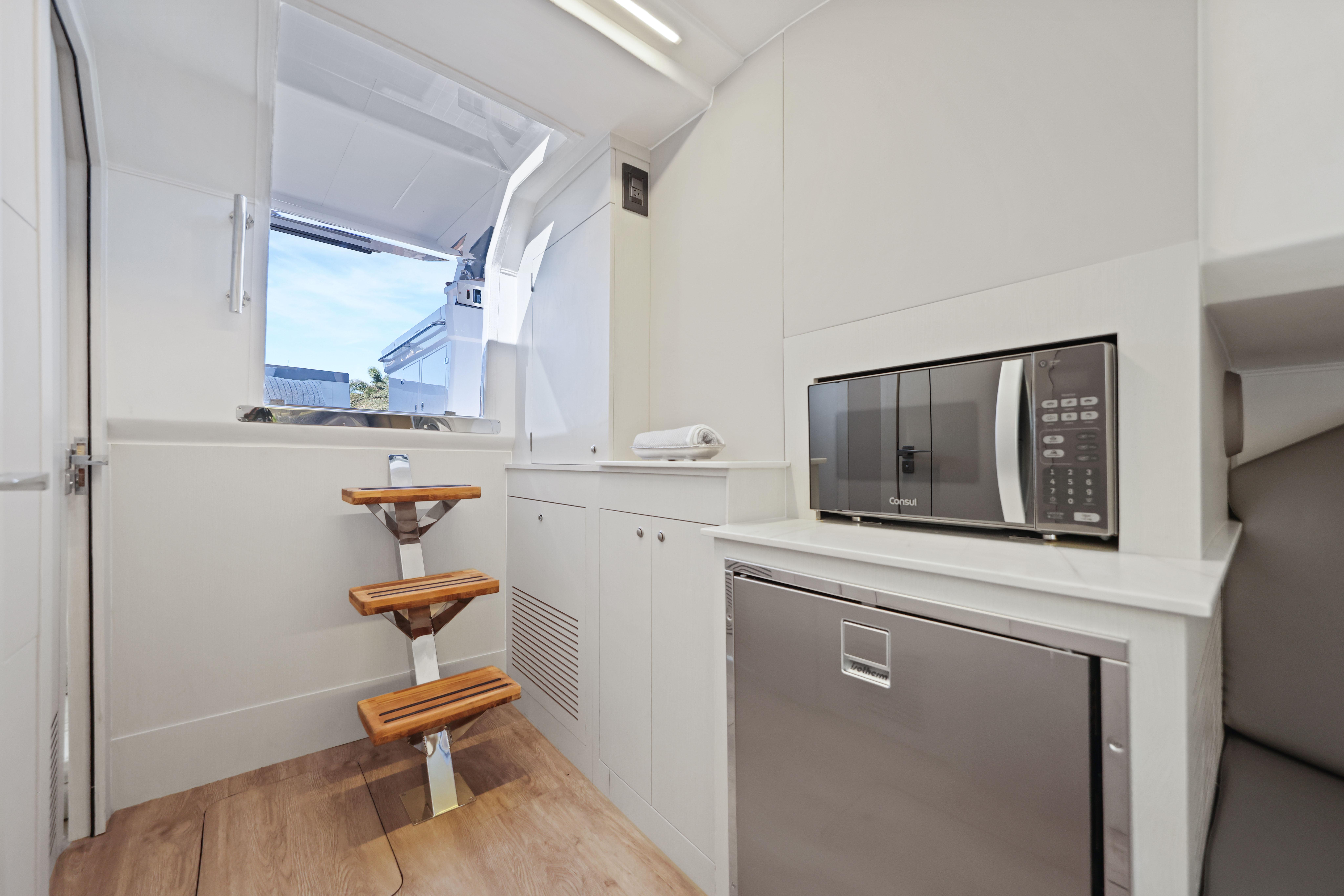Interior of 2025 Valiatt 380 Bowrider with microwave, fridge, and wooden steps.