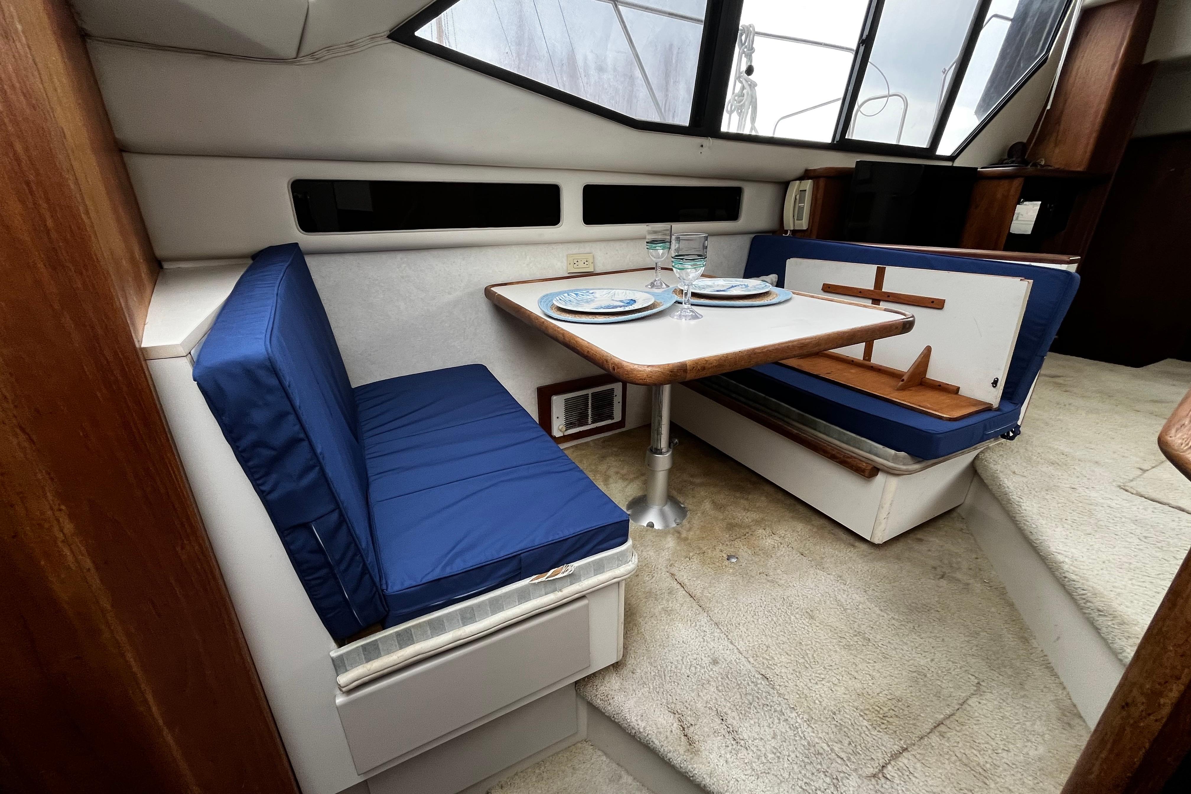 Interior of 1991 Carver 33 Aft Cabin Motor Yacht with dining area and blue cushions.