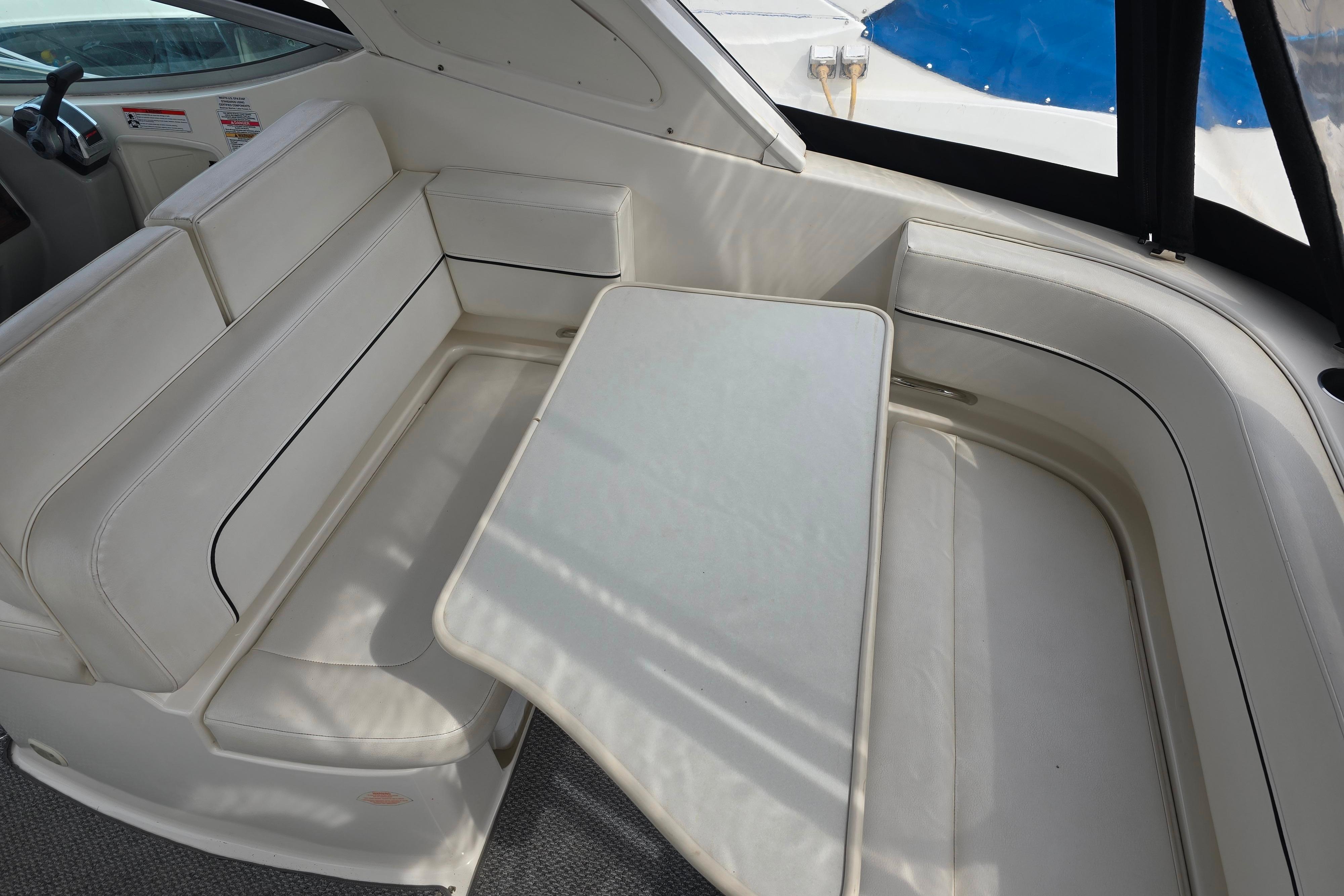 Interior seating area of a 2011 Bayliner 285 boat with a white table.