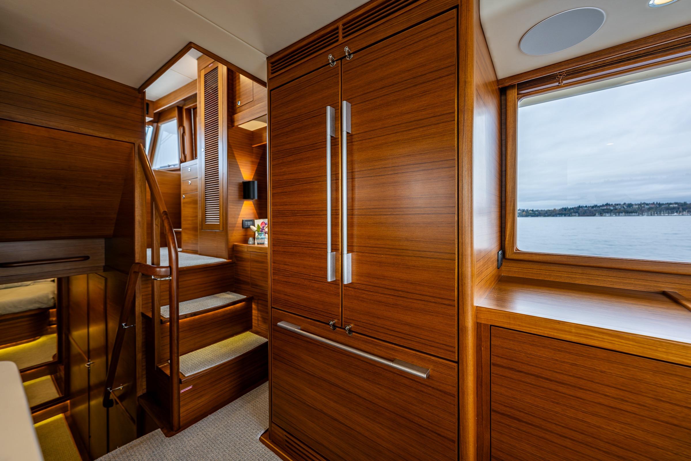 Luxurious interior of 2026 Fleming 55 Pilothouse yacht with wooden finishes and scenic window view.