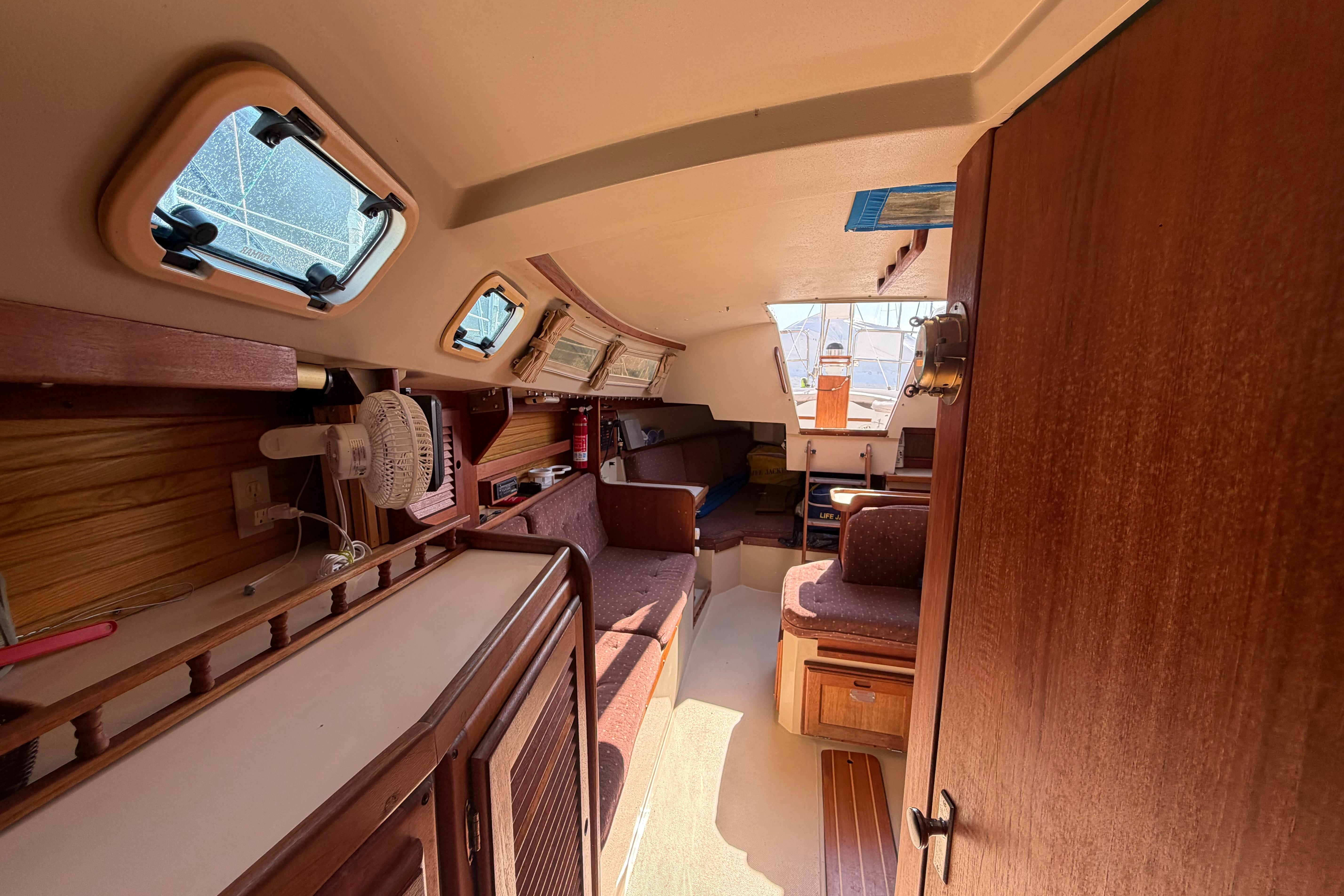 Interior of a 1988 Catalina 30 MkII sailboat, featuring cozy seating and wooden finishes.