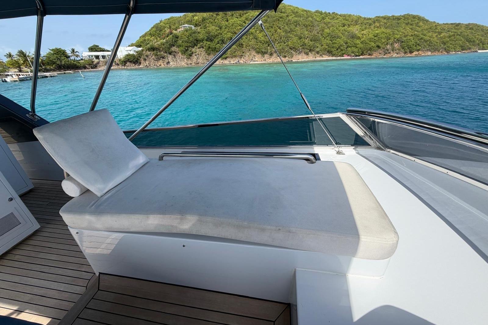Luxurious 2012 Sanlorenzo SL72 yacht deck with sunbed, overlooking turquoise waters and lush island scenery.