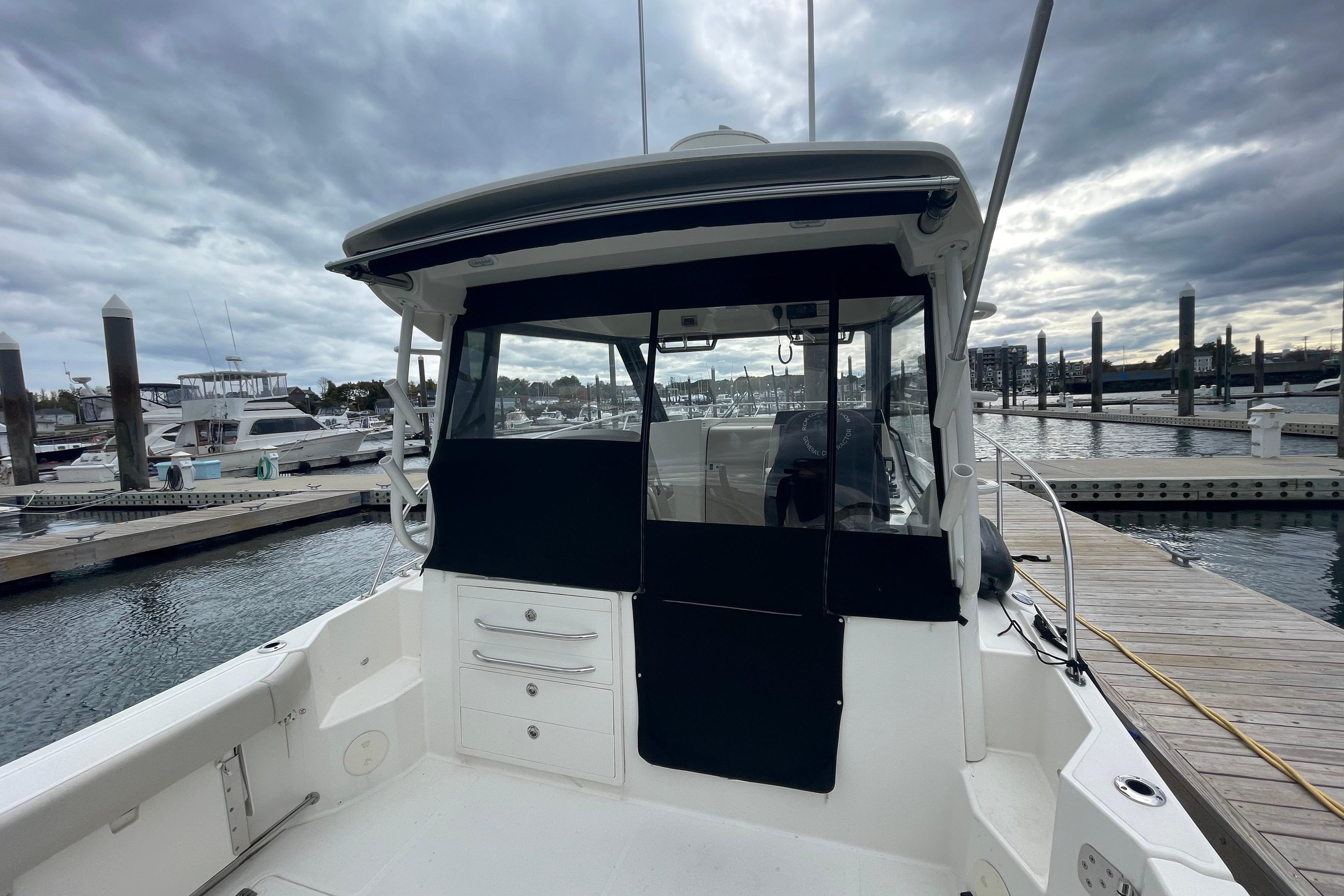 2023 Boston Whaler 325 Conquest docked at marina under cloudy sky.