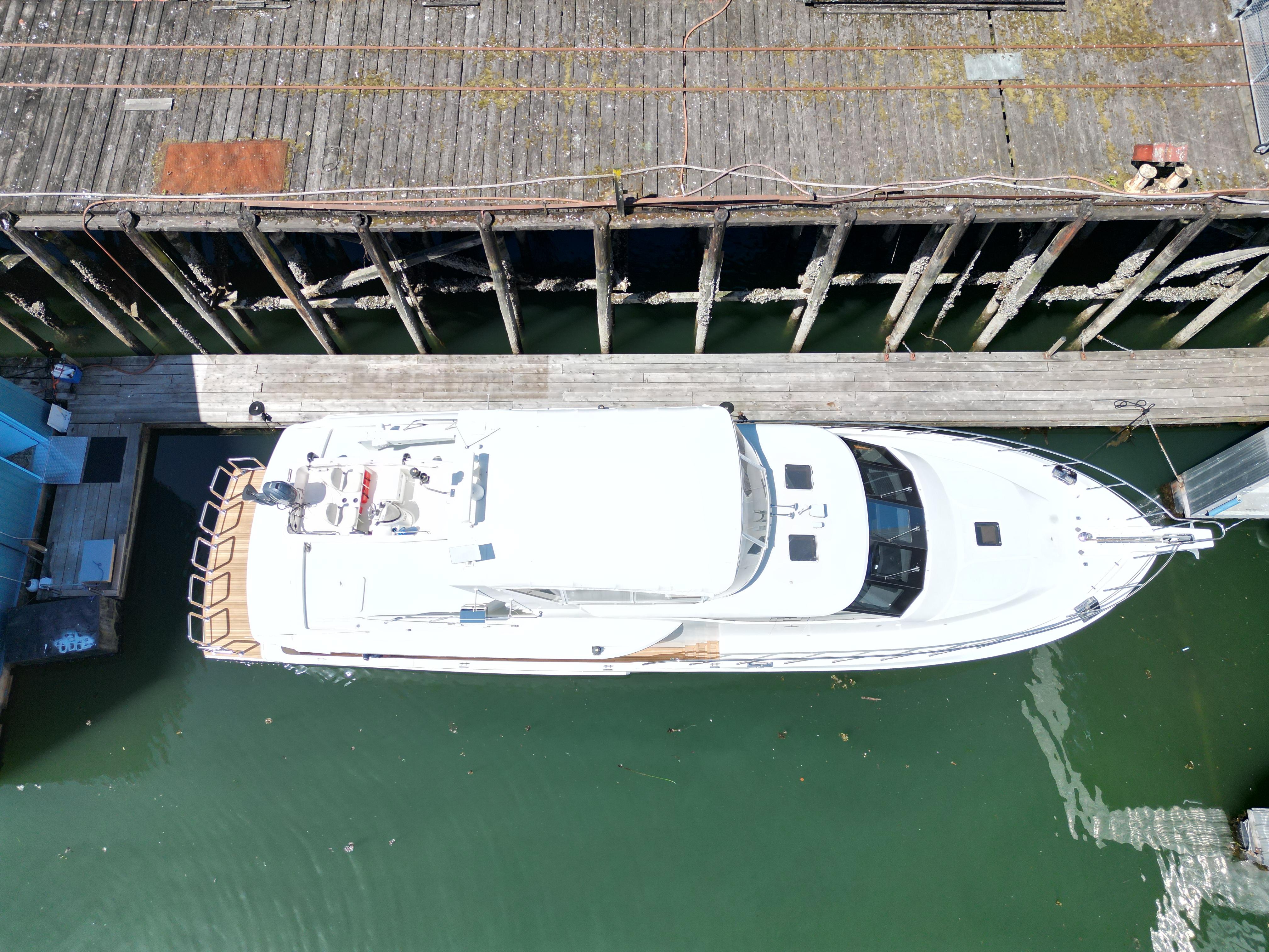 Aerial view of 2001 Symbol 66 Pilothouse Yacht docked at a wooden pier.