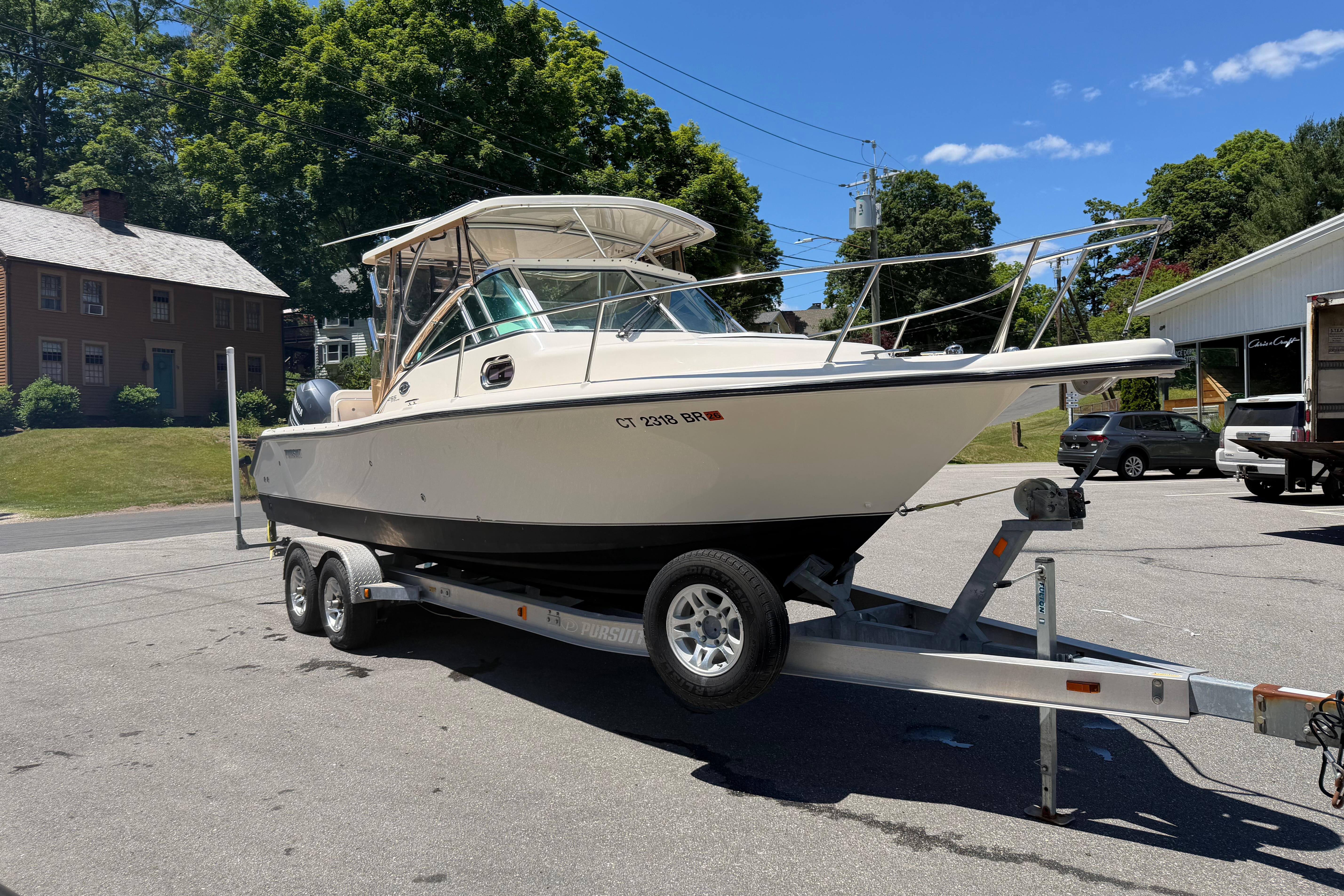2010 Pursuit OS 255 Offshore boat on trailer, parked outdoors on a sunny day.