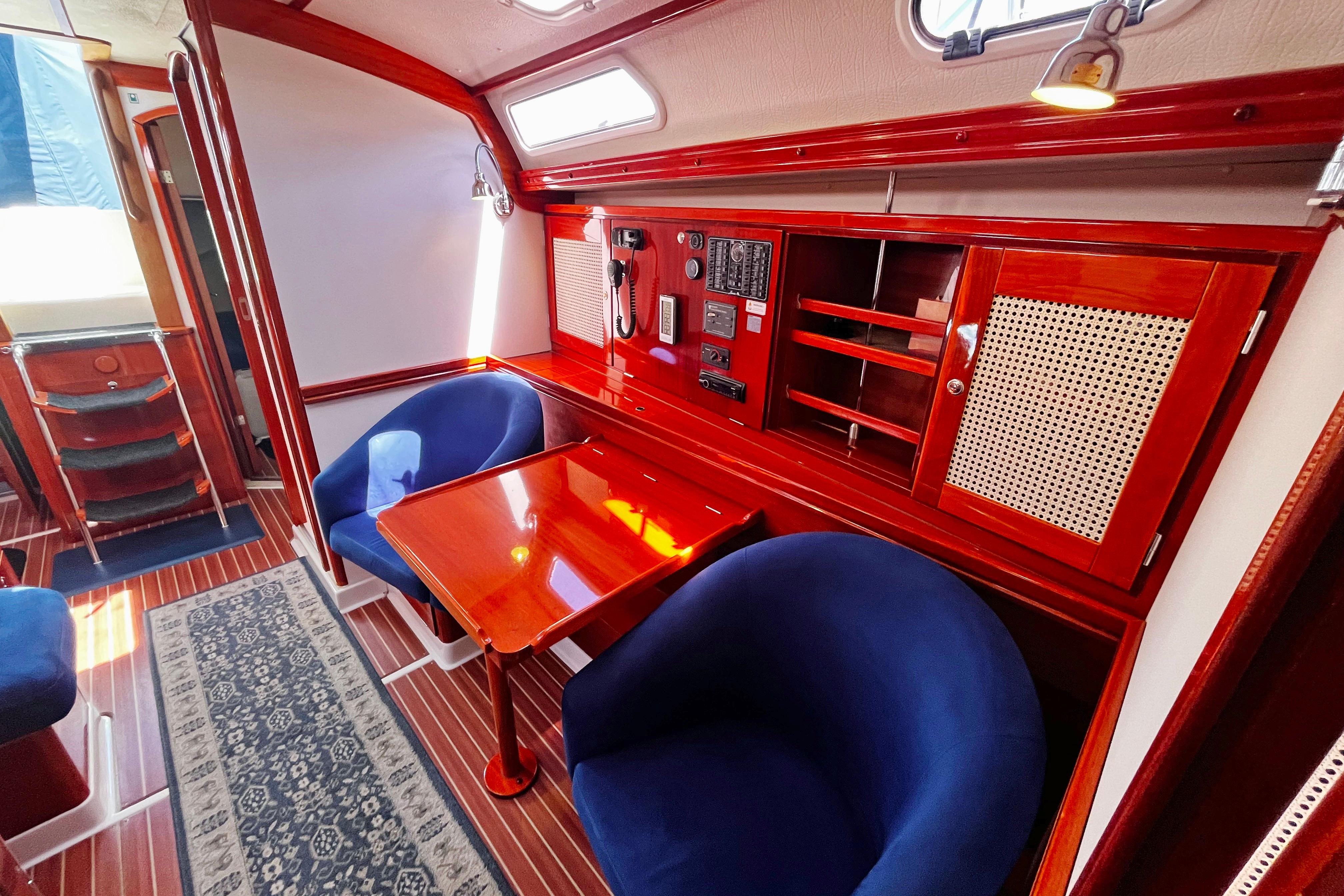 Luxurious 2004 Hanse 411 yacht interior with elegant wood finish and plush blue seating.