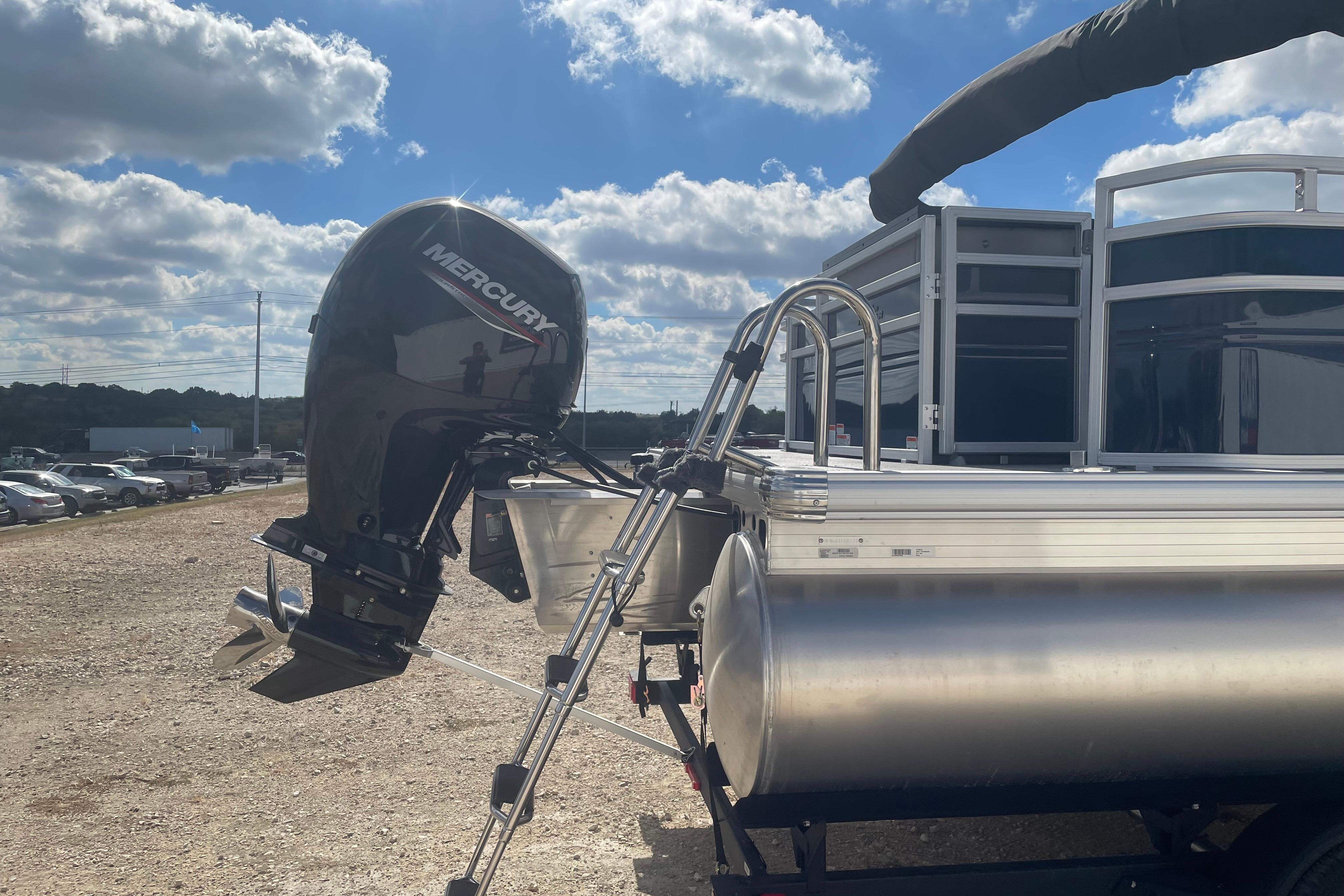 2026 Sun Tracker SportFish 22 DLX pontoon boat with Mercury outboard motor under a sunny sky.