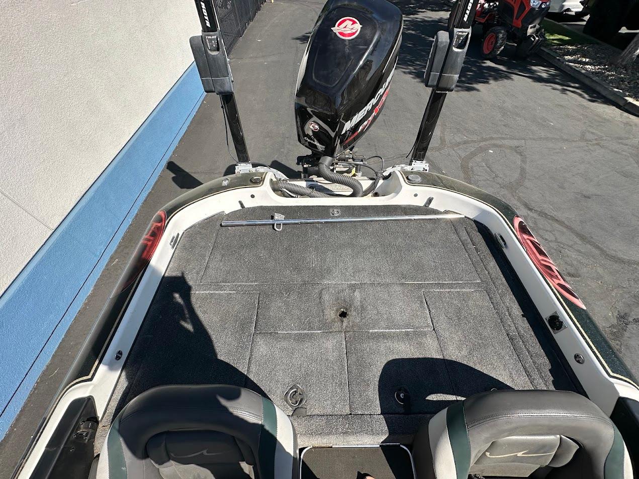 1999 Fisher 21 FX DC boat deck with Mercury outboard motor, parked on pavement.