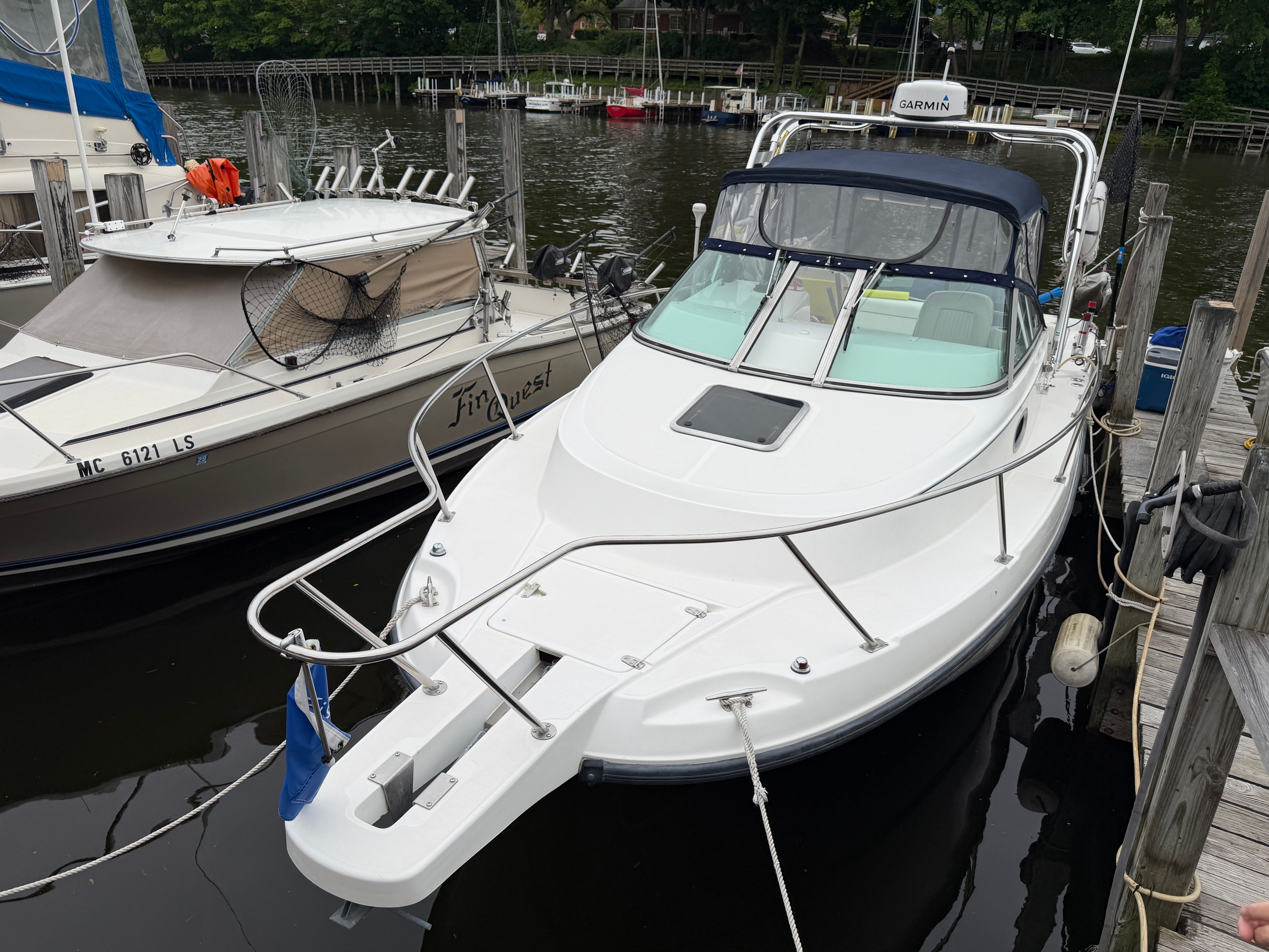 A 2001 Boston Whaler 26 Conquest docked. It features a clean, white deck.