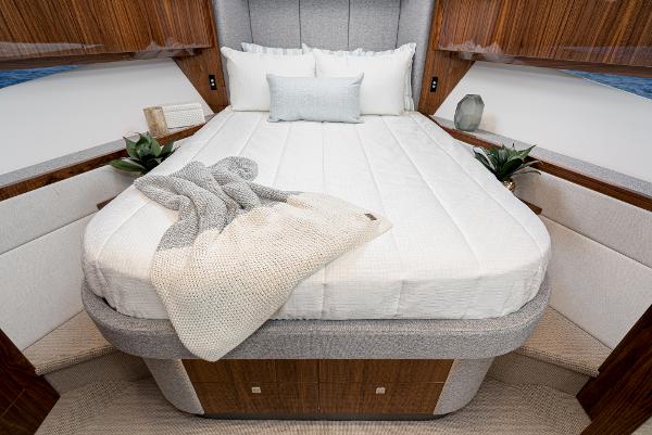 Luxurious bedroom in 2021 Riviera 5400 Sport Yacht with elegant bedding and modern decor.