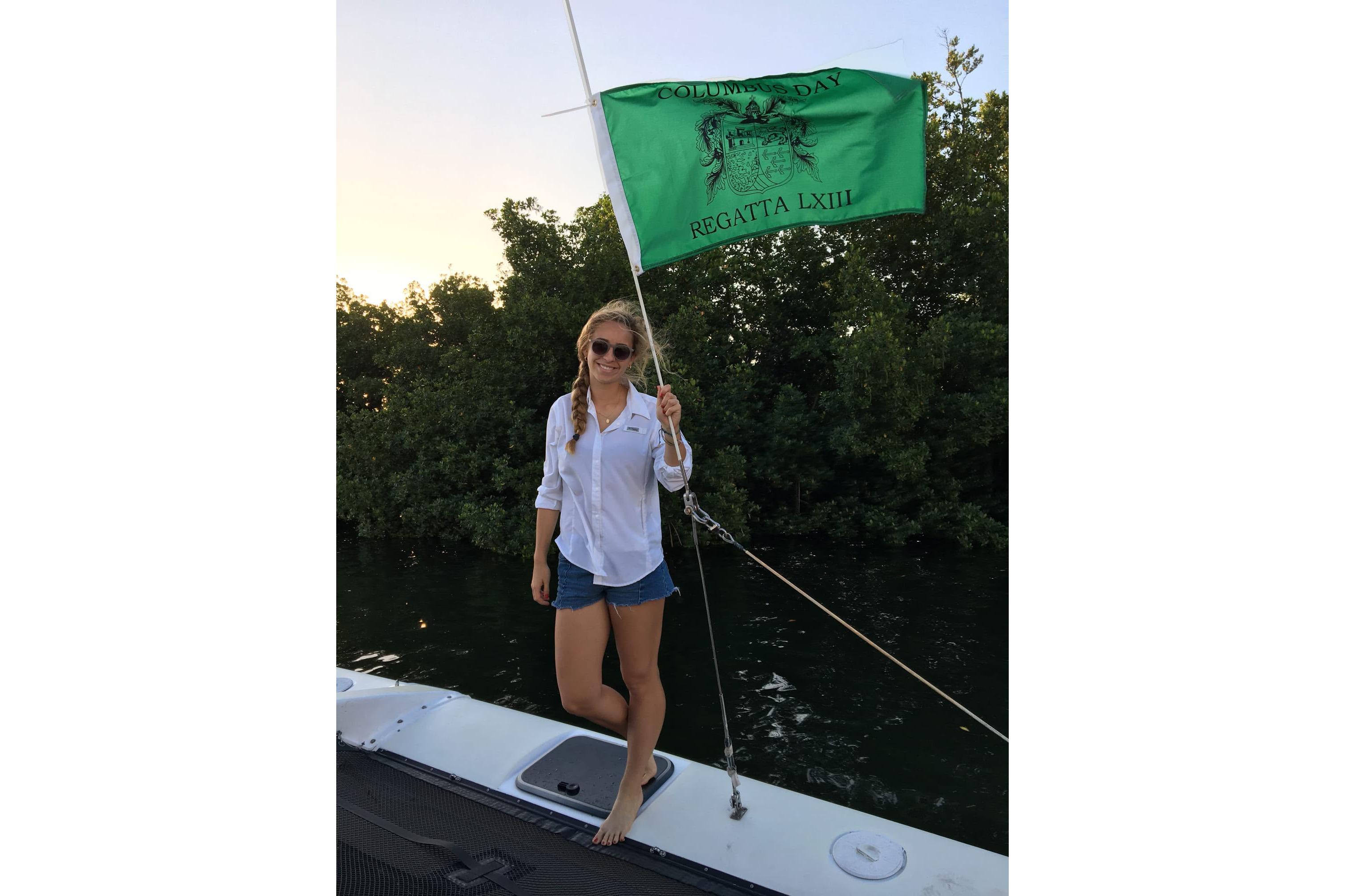 Woman on Corsair F-27 sailboat holding regatta flag, 1991 model.