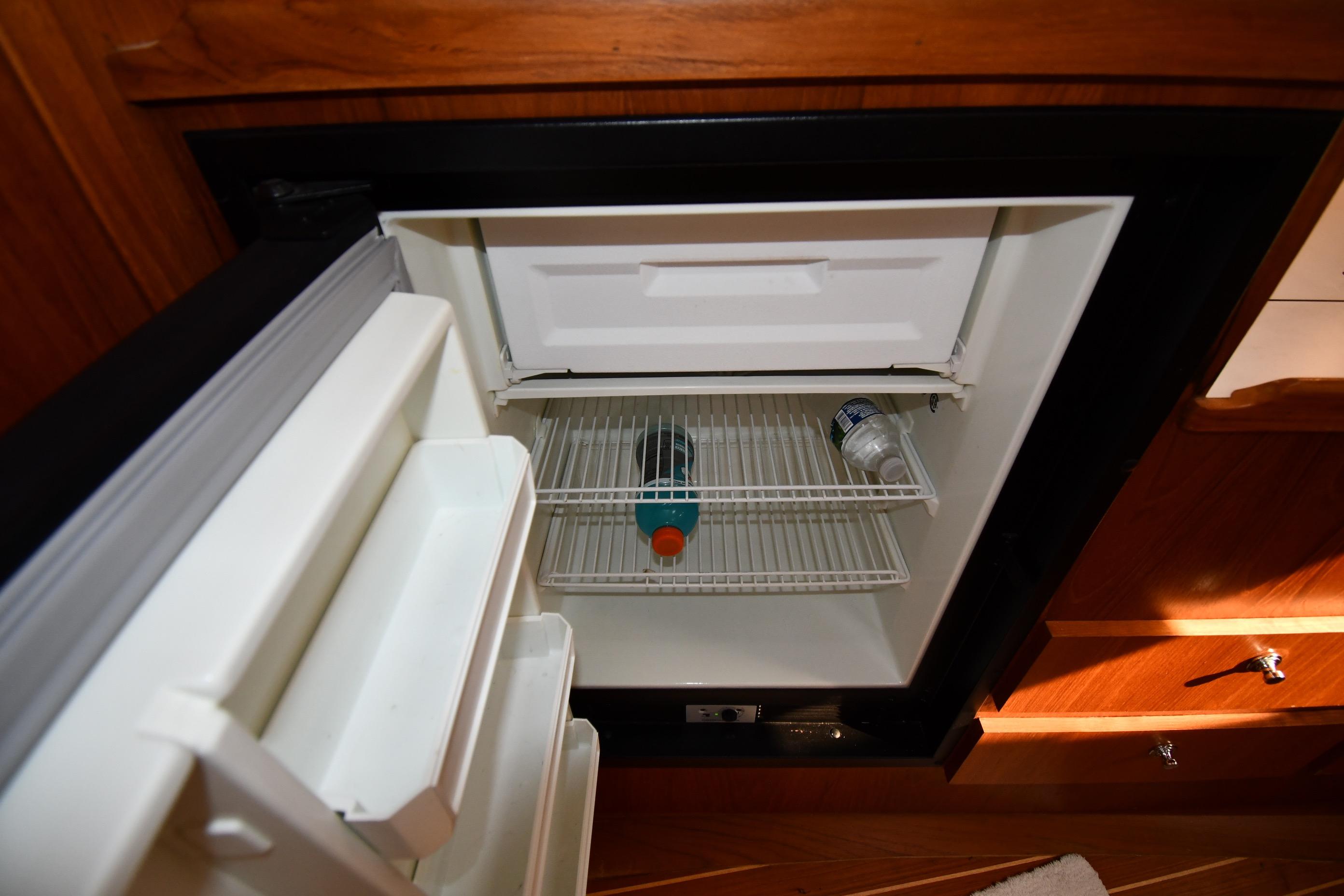 1998 Tiara Yachts 3100 Open refrigerator with drinks inside, wooden cabinetry background.