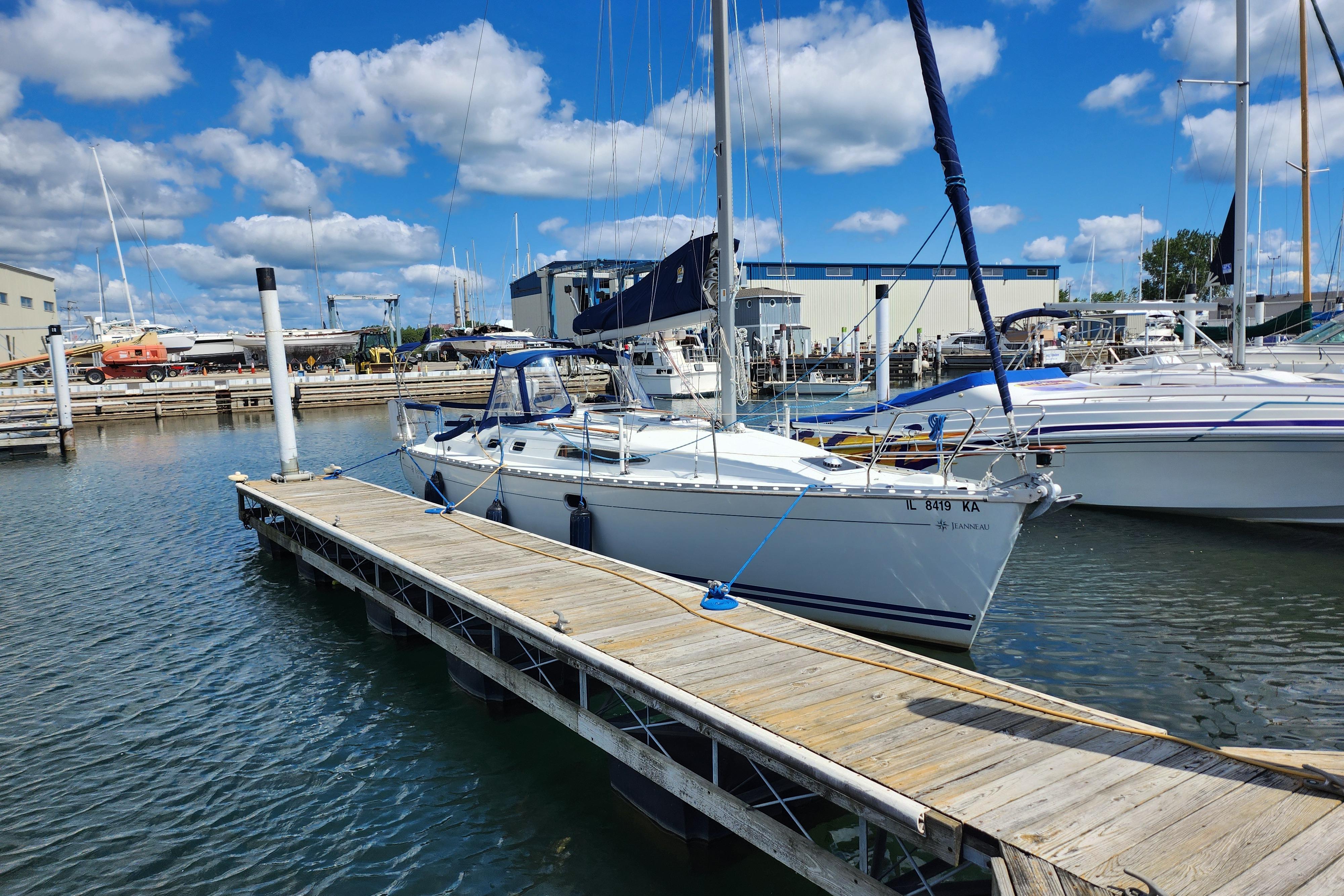 2001 Jeanneau Sun Odyssey 34.2 sailboat docked at a marina under blue skies.