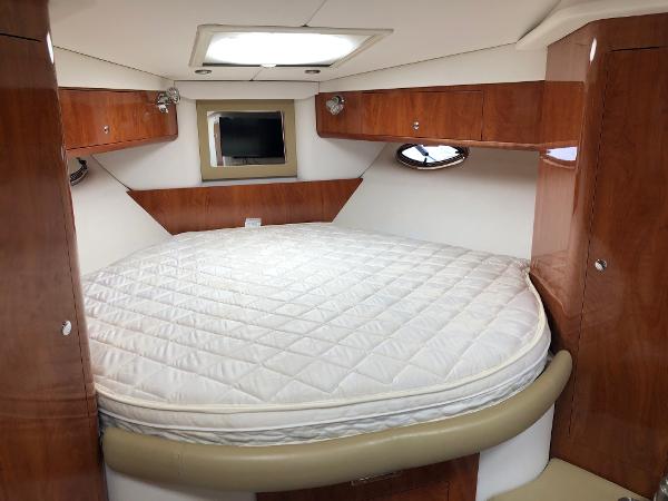 Interior of the 2008 Four Winns V338 with a cozy bed and wood paneling.