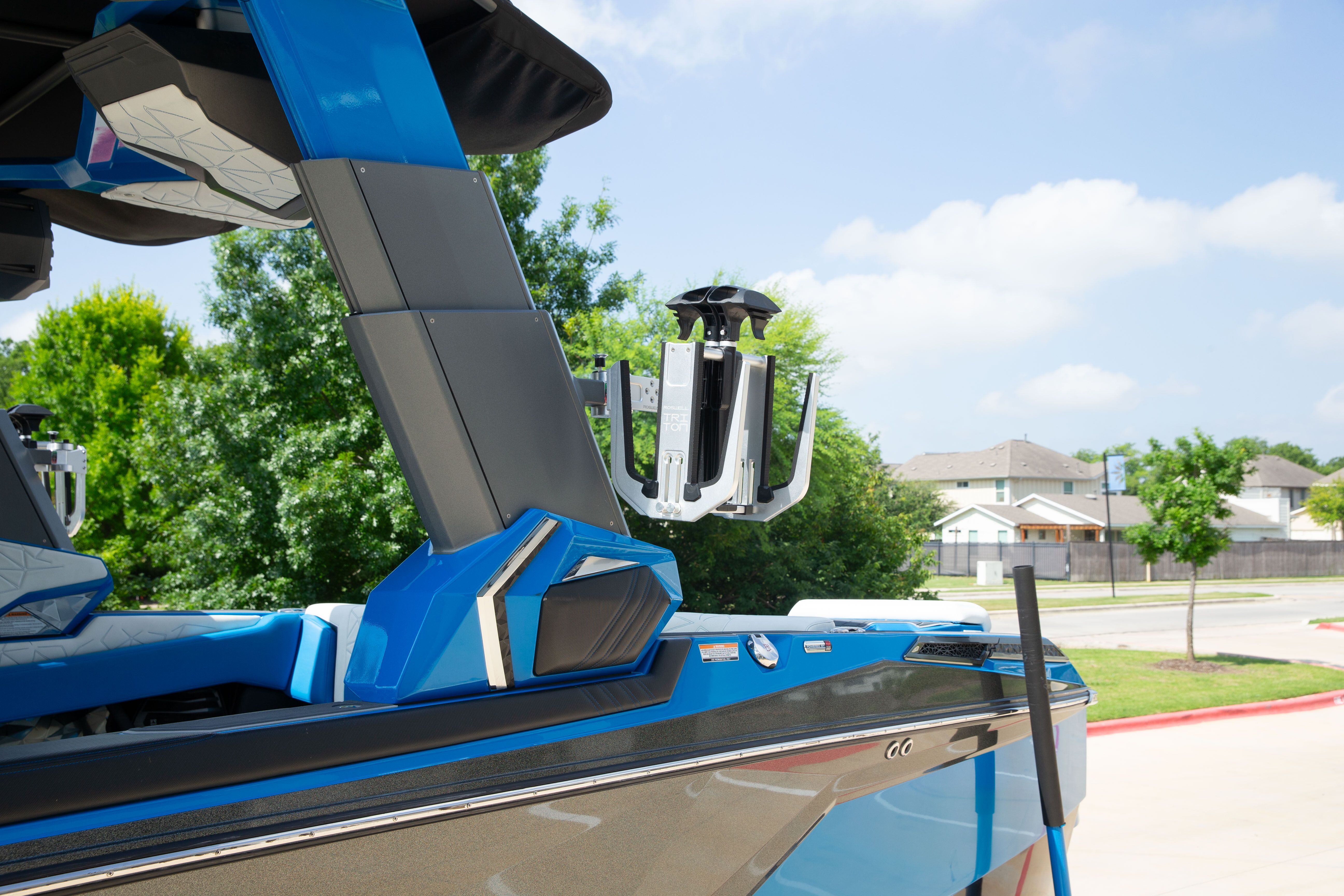 A blue boat with modern design elements is parked on a driveway.