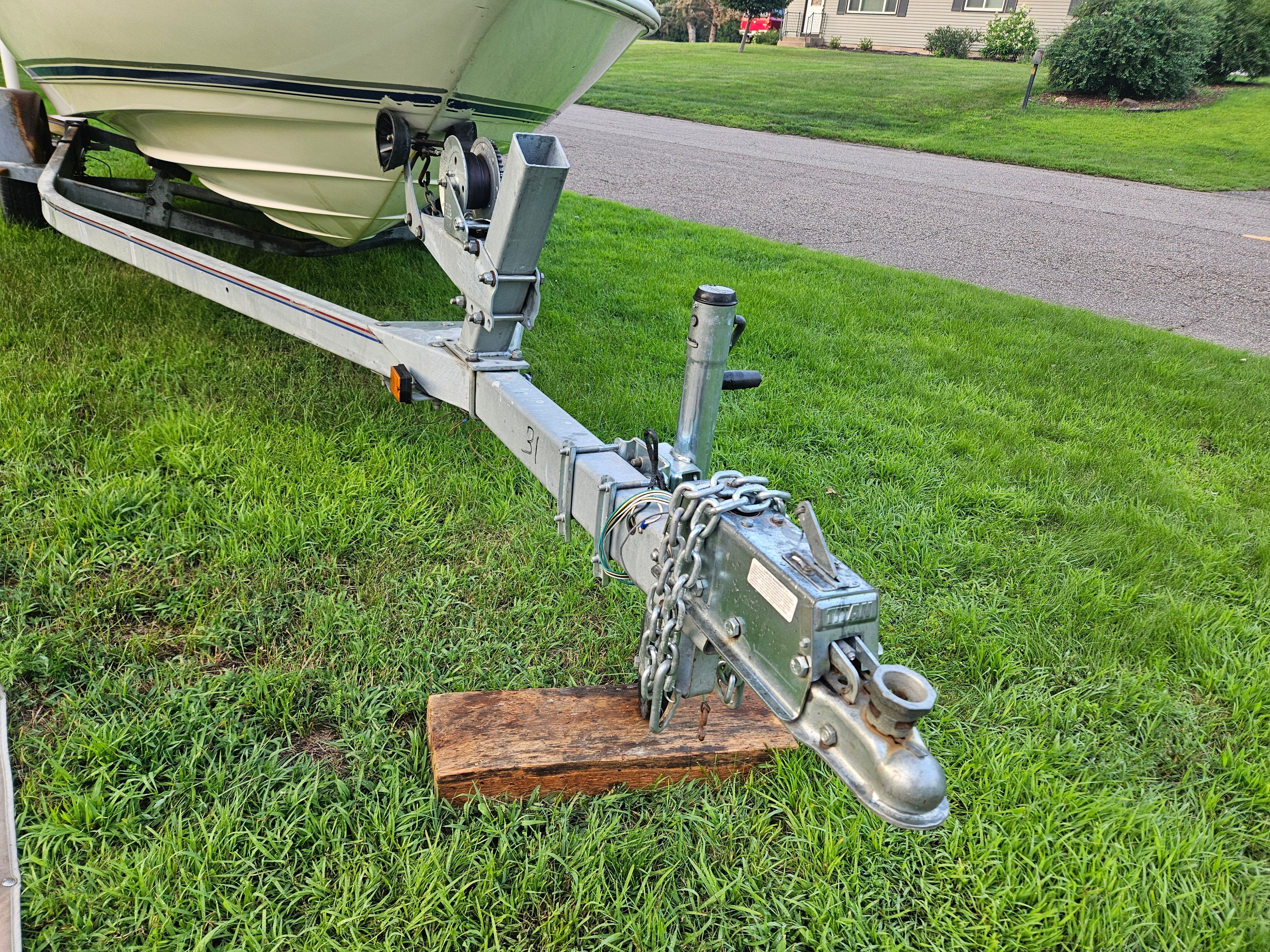 A 1996 Wellcraft Excel boat on a trailer, parked on a grassy lawn.