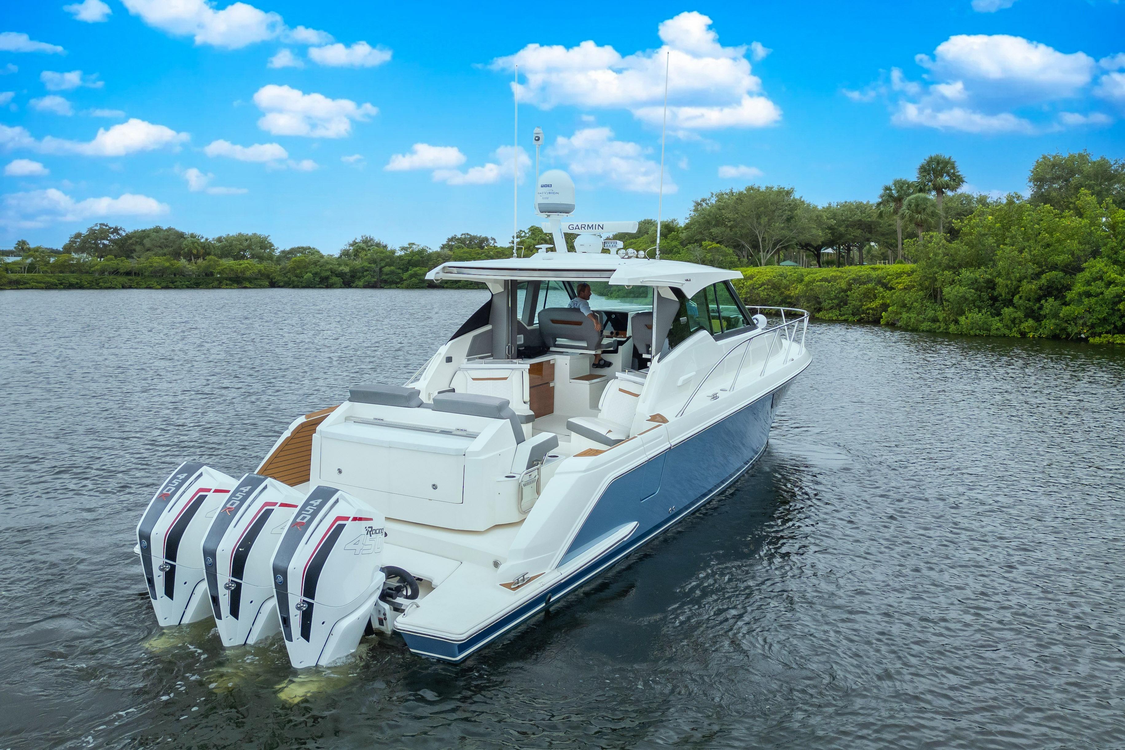 2021 Tiara Sport 43 LE boat cruising on a scenic waterway under a blue sky.